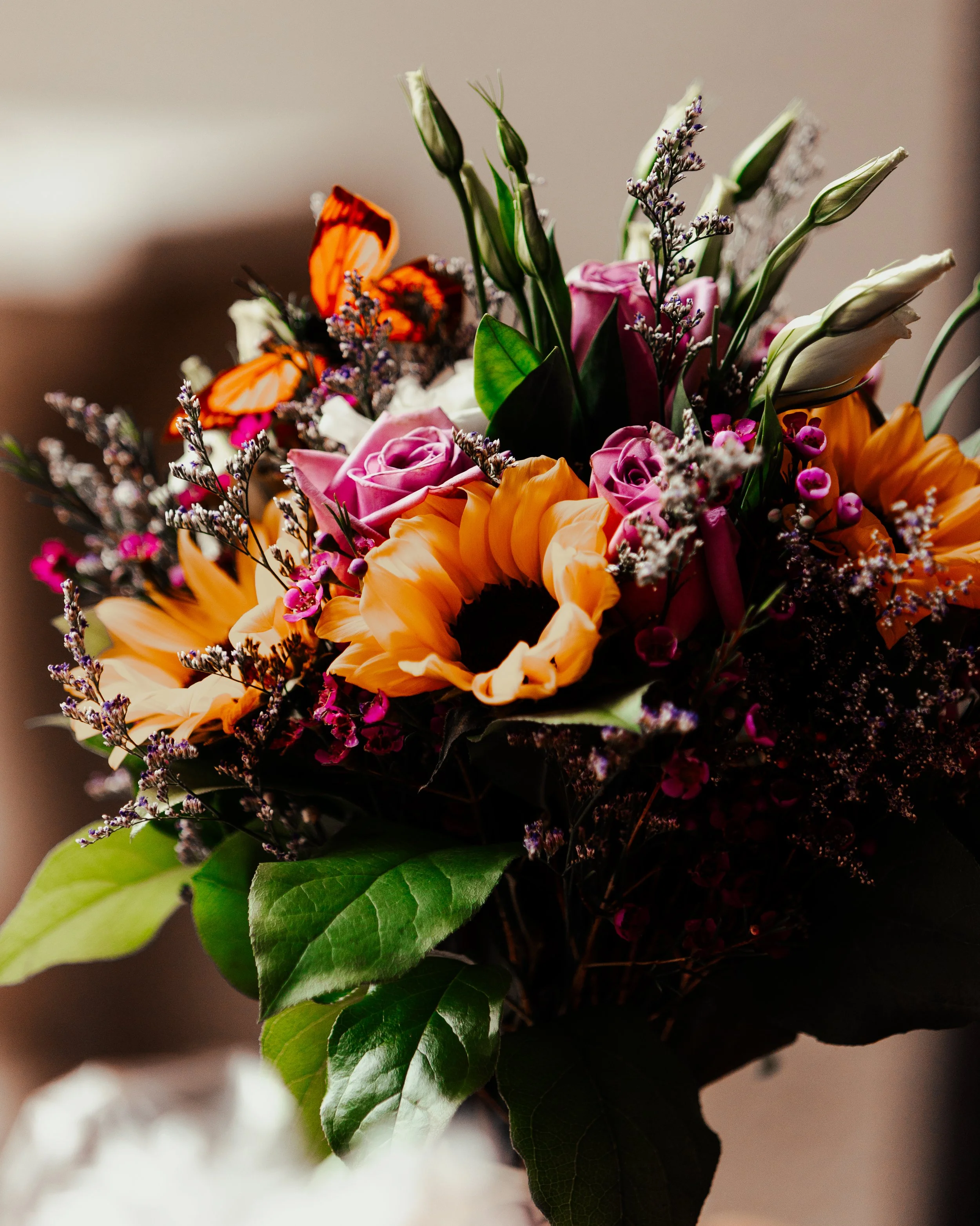 A colorful bouquet of flowers including sunflowers, roses, lilies, and butterflies.