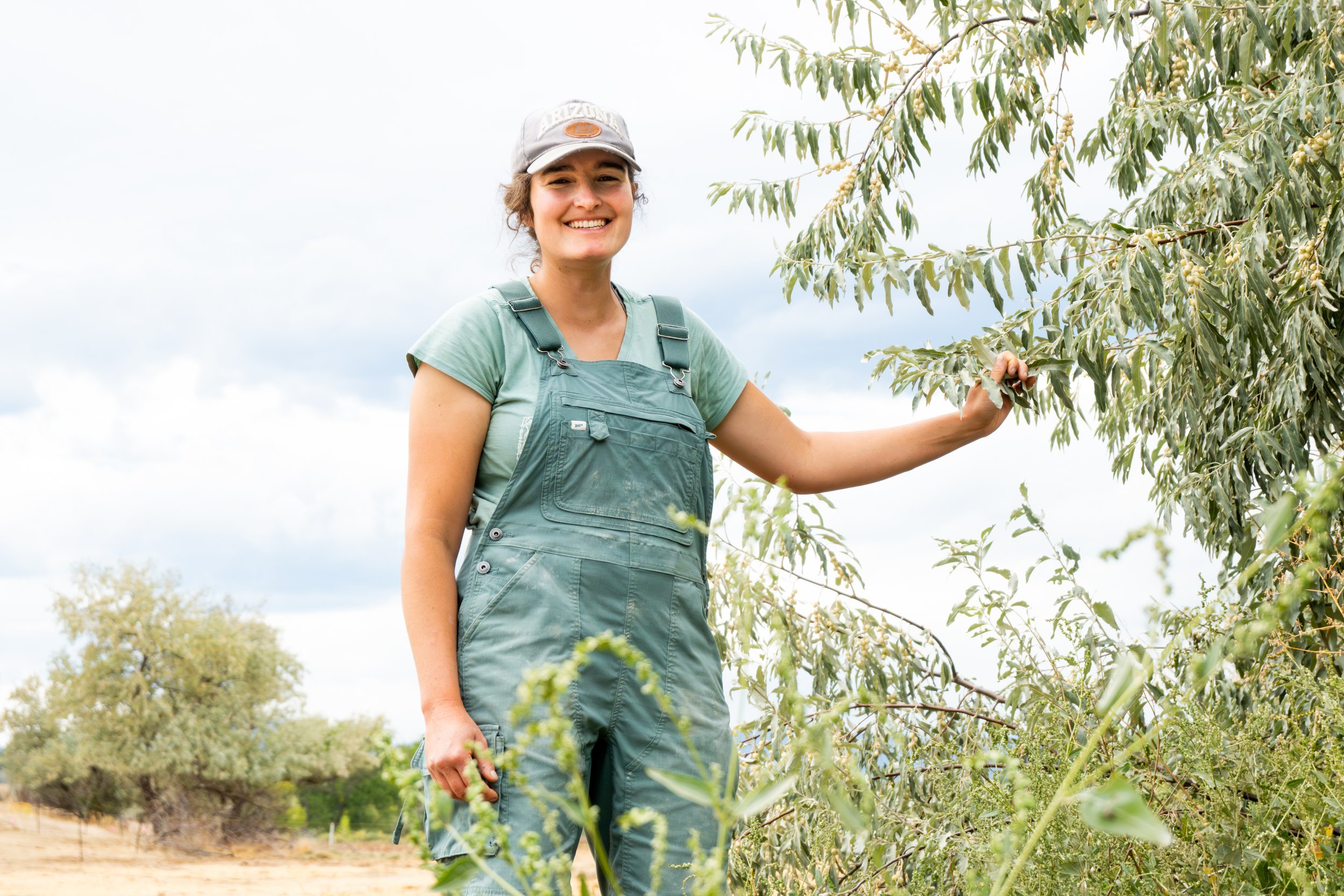 A High Plains Permaculture employee stands by a tree on the property