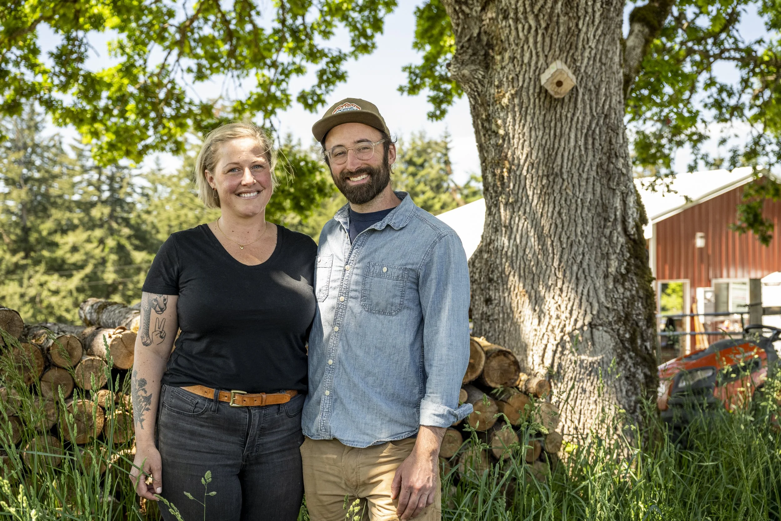 Zach and Christina Menchini stand together in front of their farm