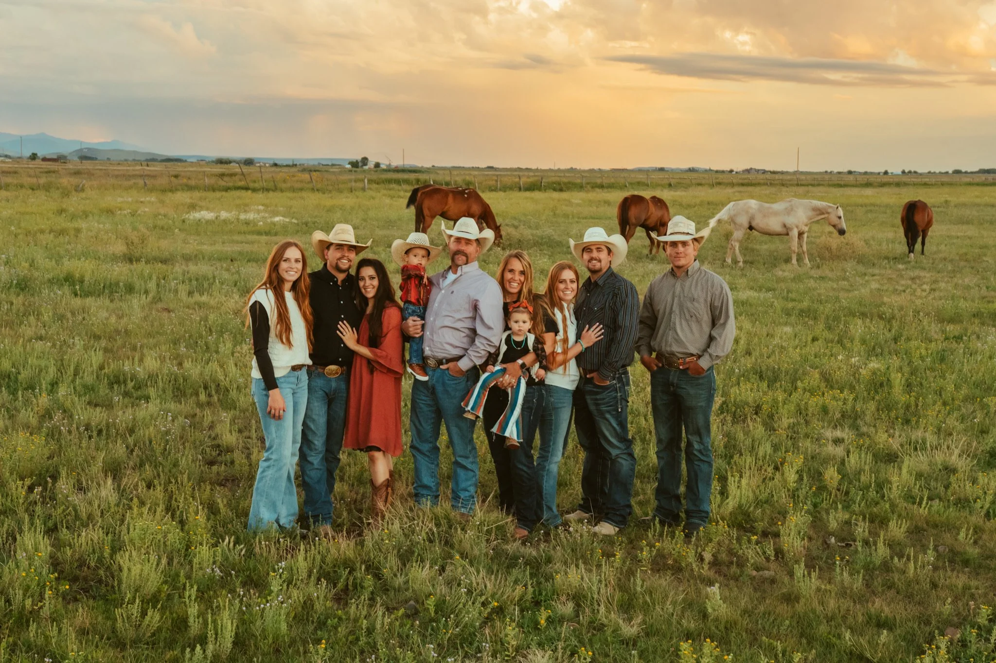 A family of ranchers in a field of horses grazing