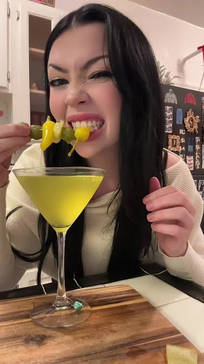 Holly Barnes bites a pepperoncini garneish from an extra dirty martini
