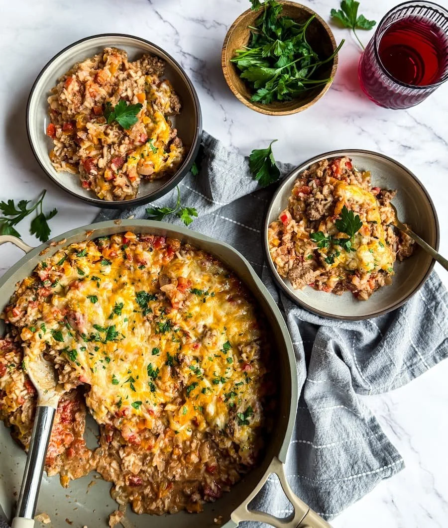 overhead view of stuffed pepper casserole with two bowls of casserole next to the pan
