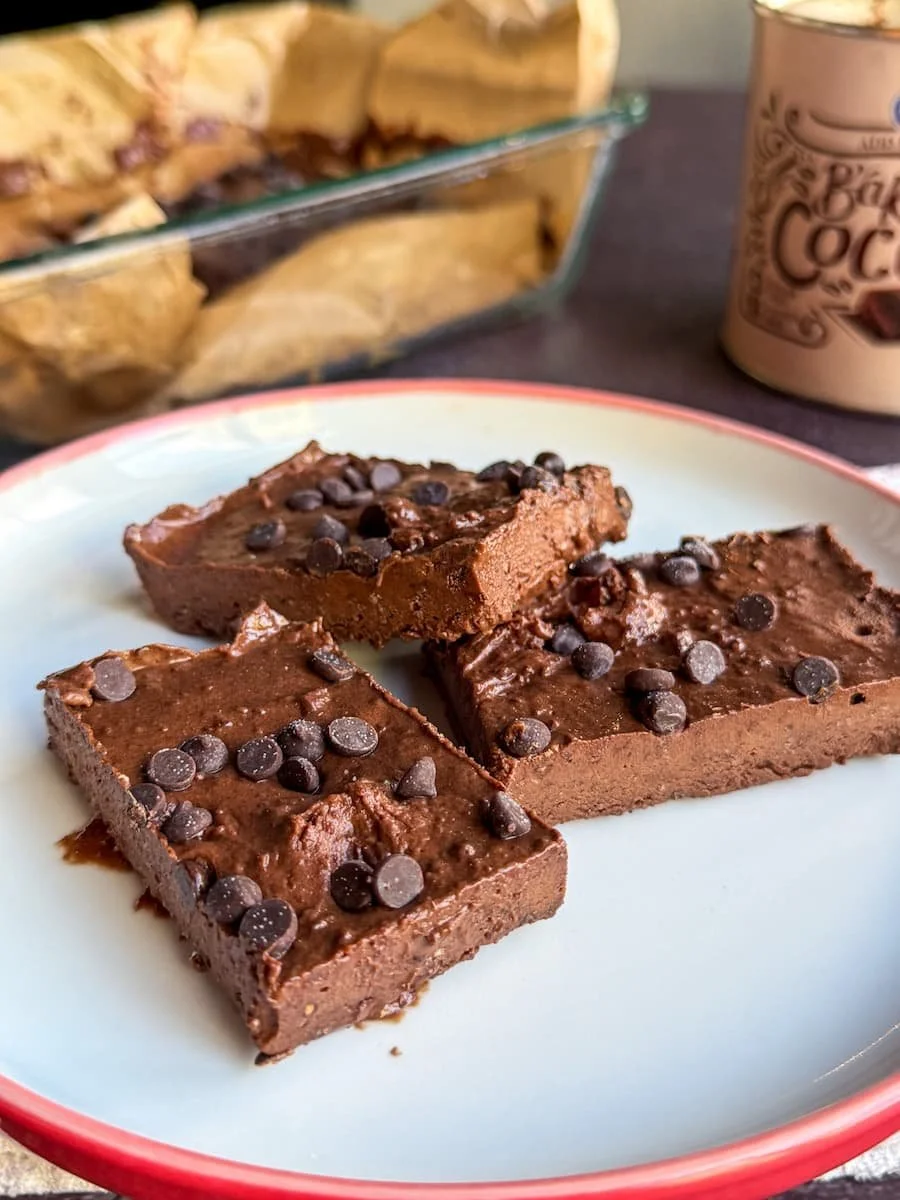 cottage cheese fudge - close-up shot of 3 pieces of fudge on a plate with the pan of fudge behind