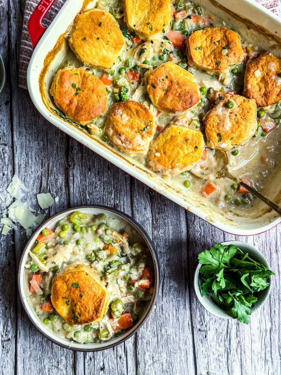 chicken pot pie casserole with a bowl of it next to the pan / shredded chicken recipes