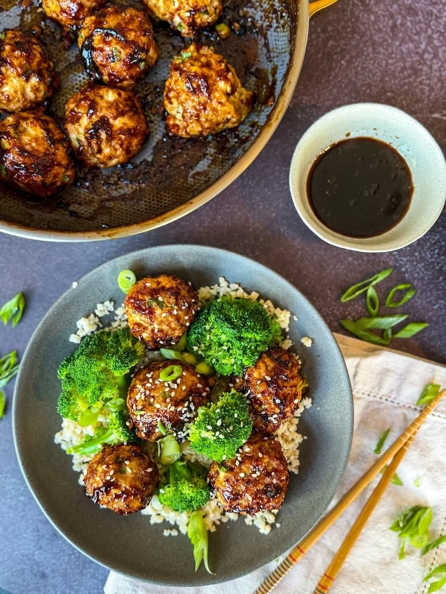 overhead shot of glazed turkey meatballs and steamed broccoli over cauliflower rice with sesame seeds and green onions