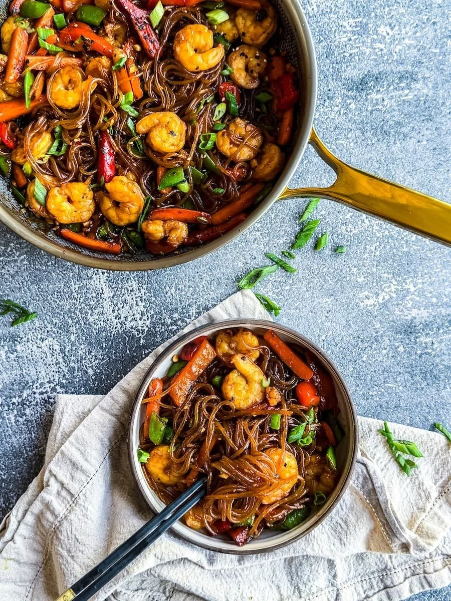 overhead photo of shrimp lo mein with chopsticks in the bowl
