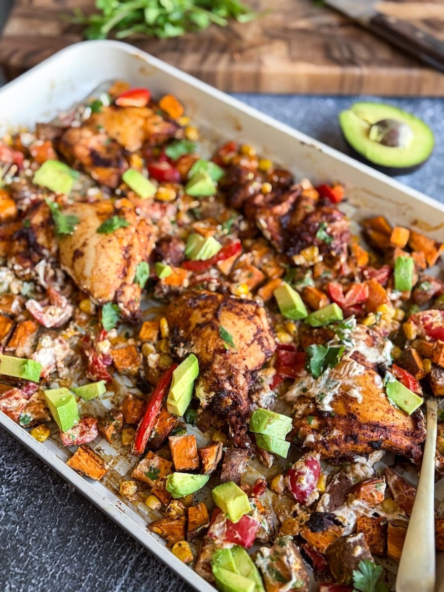overhead photo of chipotle chicken and veggies sheet pan meal with creamy avocado and fresh cilantro