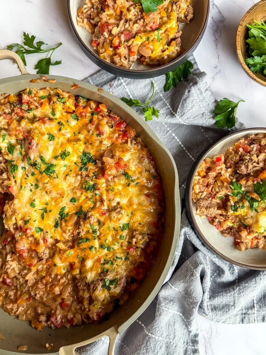 pan of stuffed pepper casserole with 2 bowls of casserole next to it
