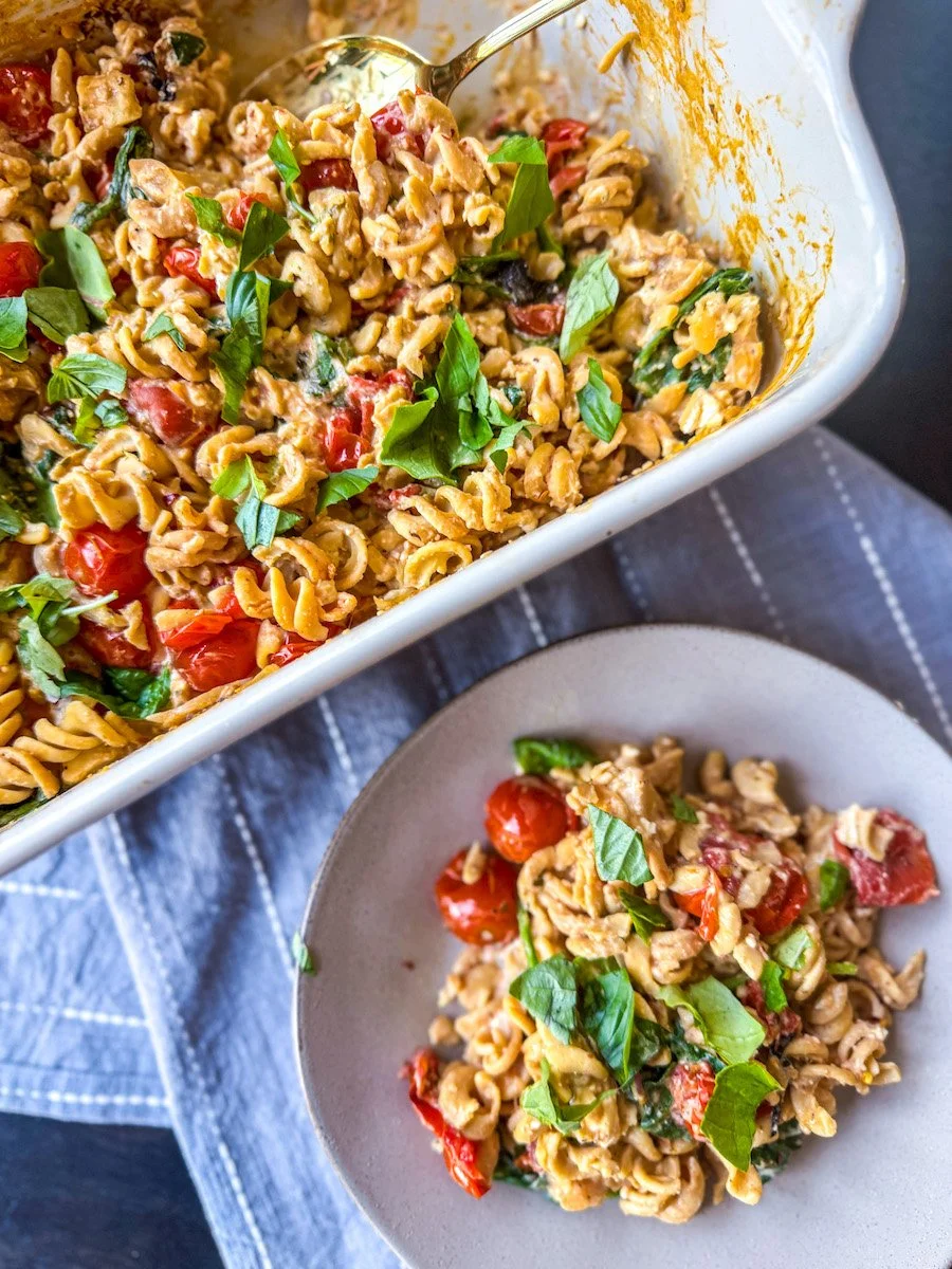 overhead photo of tomato feta pasta with a portion on a plate