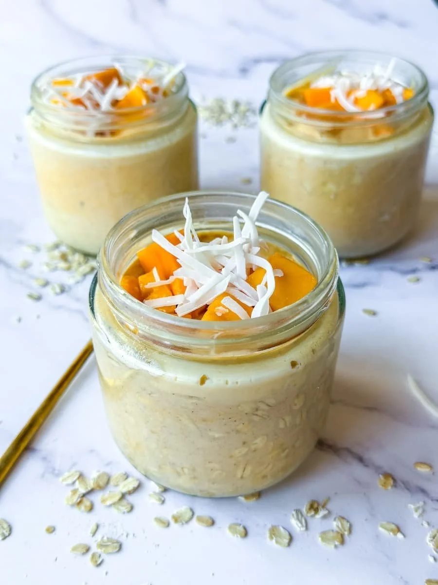 close-up photo of protein overnight oats garnished with mango and coocnut