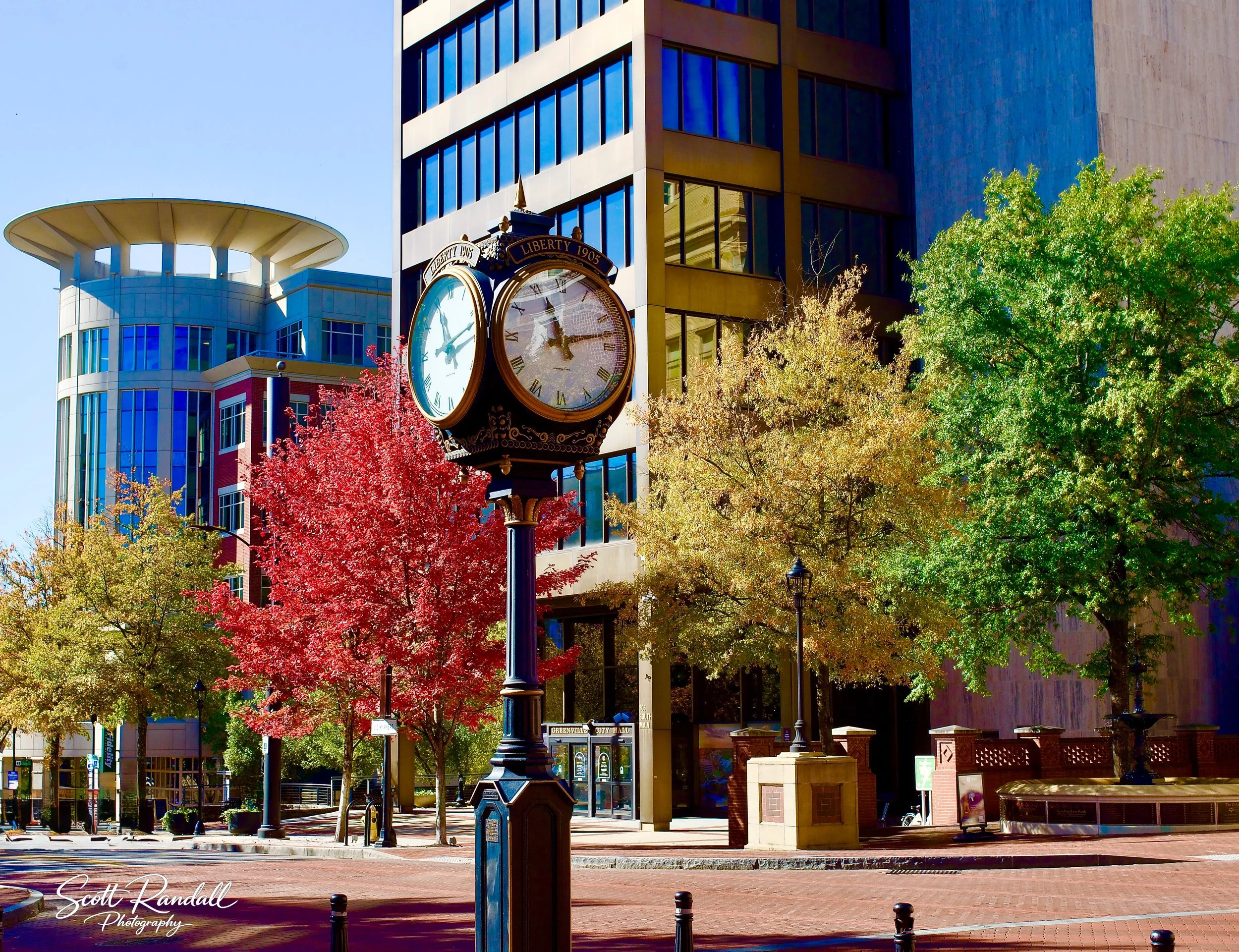 "Falling For Greenville". This was taken in downtown Greenville, SC.  Main Street near East Court Street.  Love this view with the different colors of trees as well as the Liberty Clock in foreground.