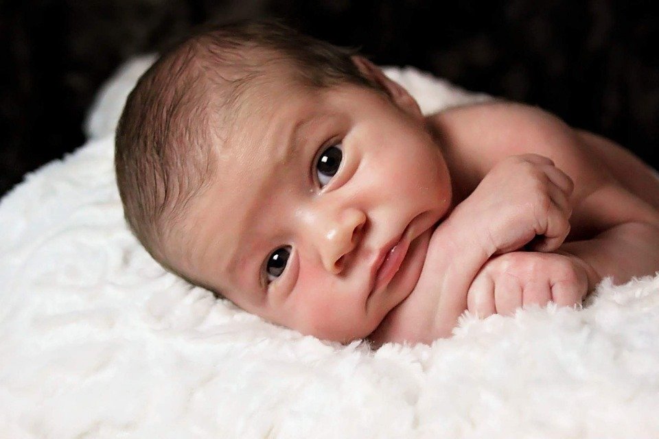 newborn baby on white blanket eyes open