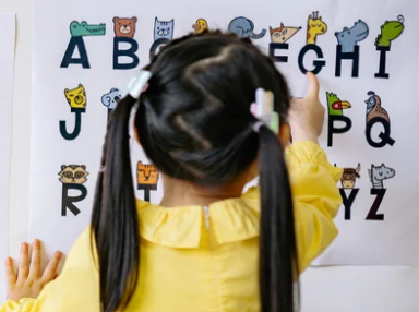 This is a photo of a young girl pointing at the alphabet