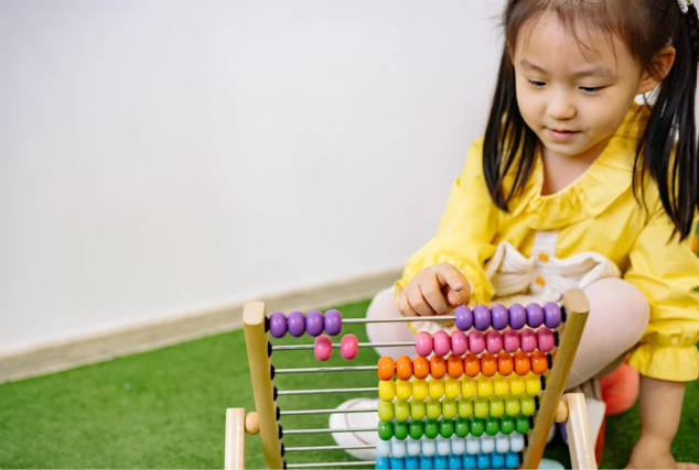 This is an image of a child counting with an abacus