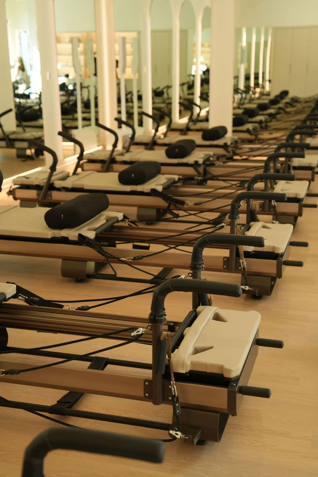 An angle view of the san studio fitness studio, showing rows of pilates reformers and tall arched mirrors.