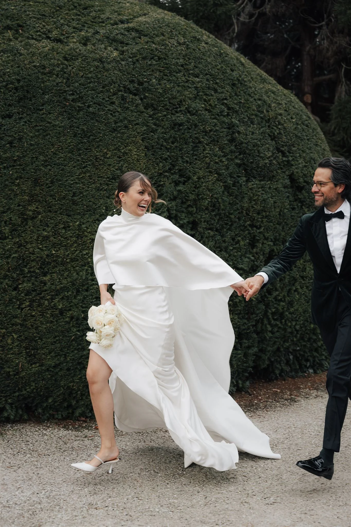 Hochzeitspaar rennend vor großem Busch