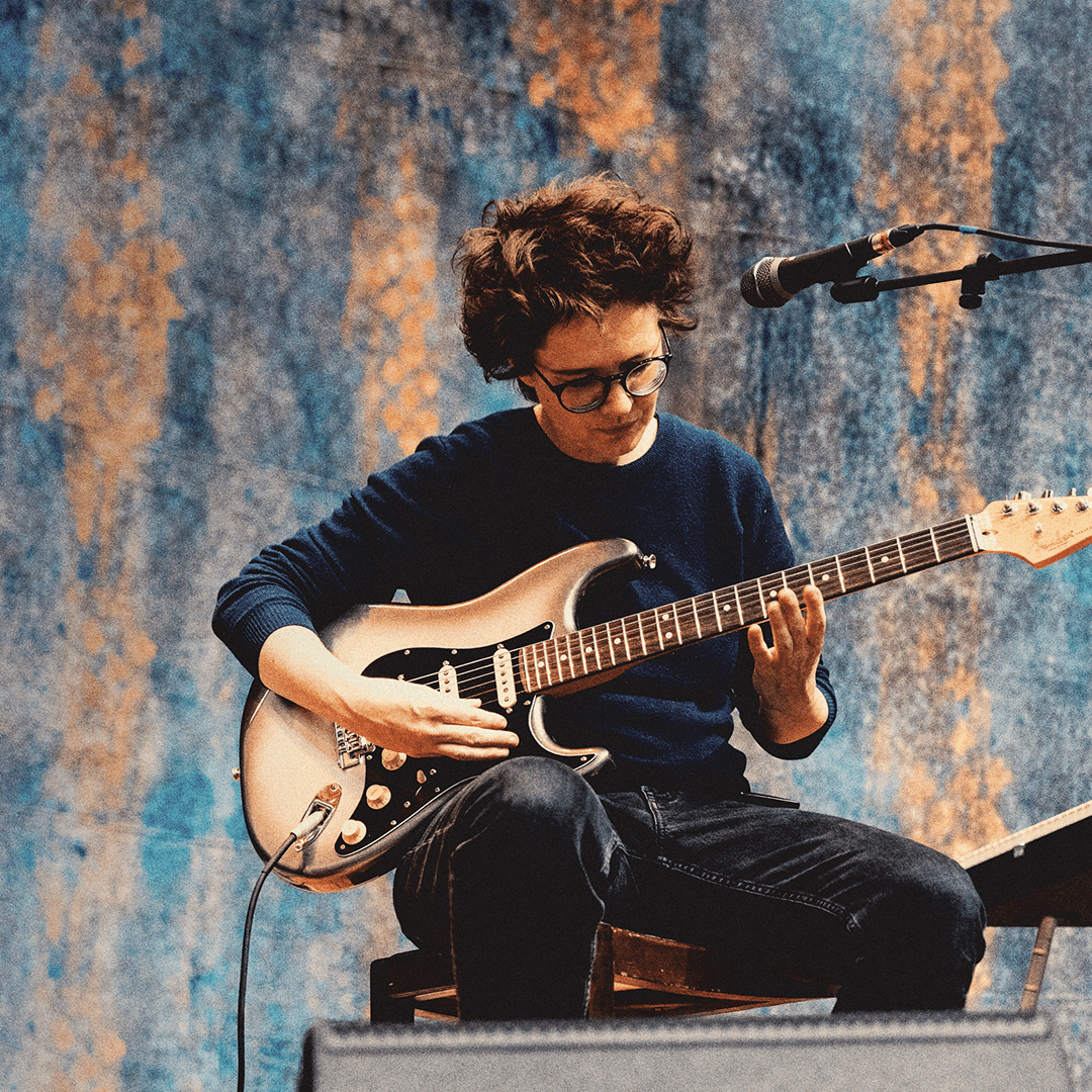 Billede af Marie Key, der spiller guitar under en akustisk koncert.