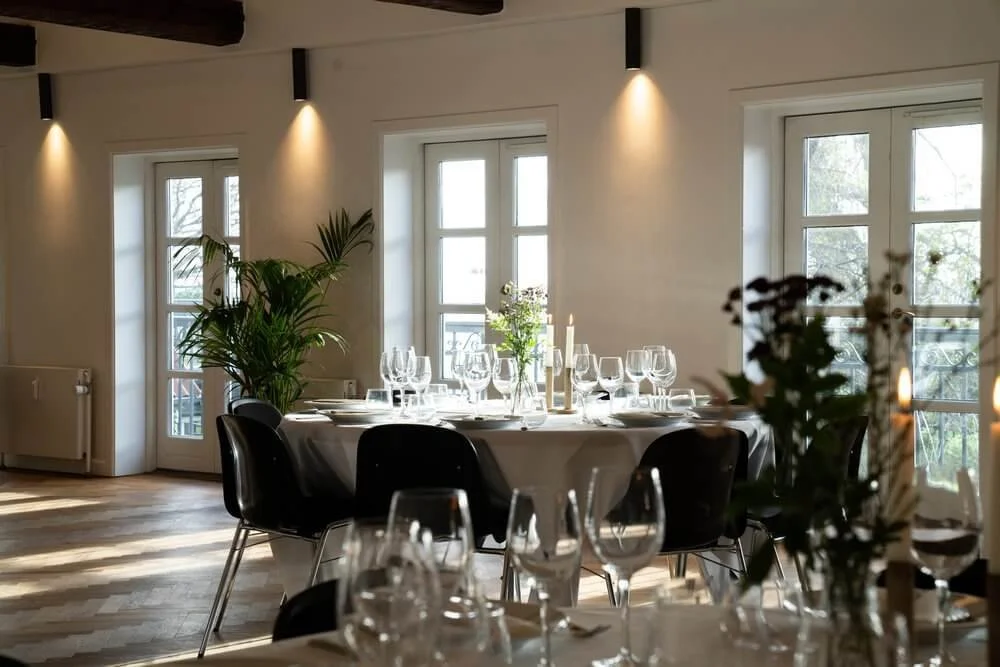 Stilfuldt spisestue med naturligt lys og moderne indretning – Ideel til bryllupper og formelle arrangementer.