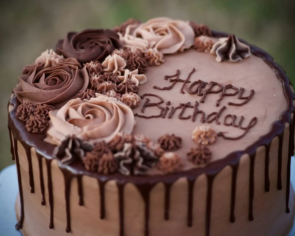 Fødselsdagskage med ‘Happy Birthday’ - Smukt dekoreret fødselsdagskage med skriften ‘Happy Birthday’ i chokoladeglasur.