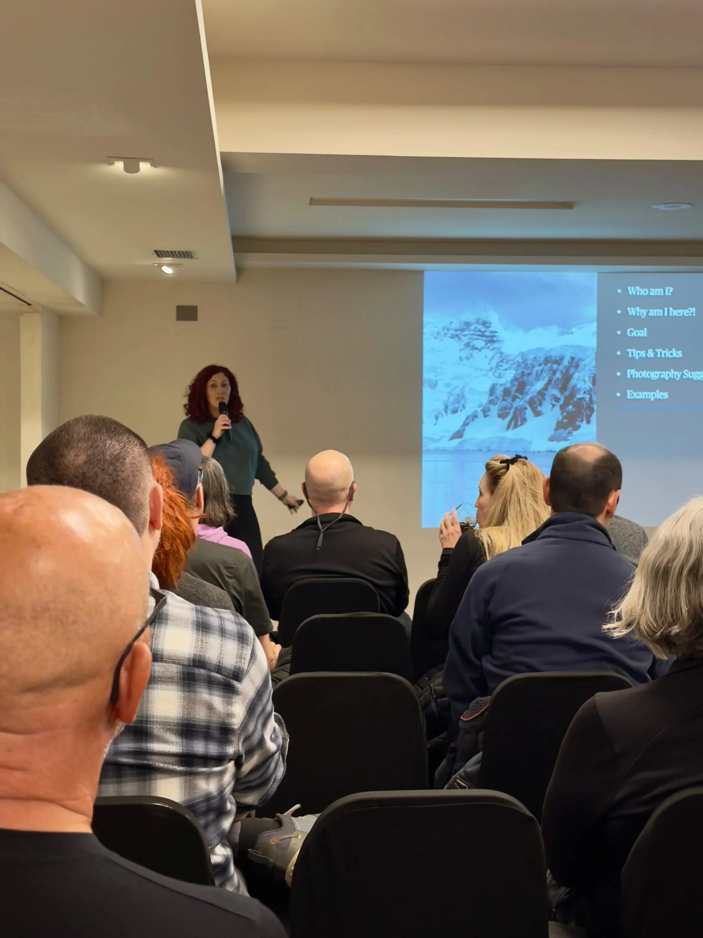 Rhiannon giving a presentation in a conference room with an audience before setting sail to Antarctica.
