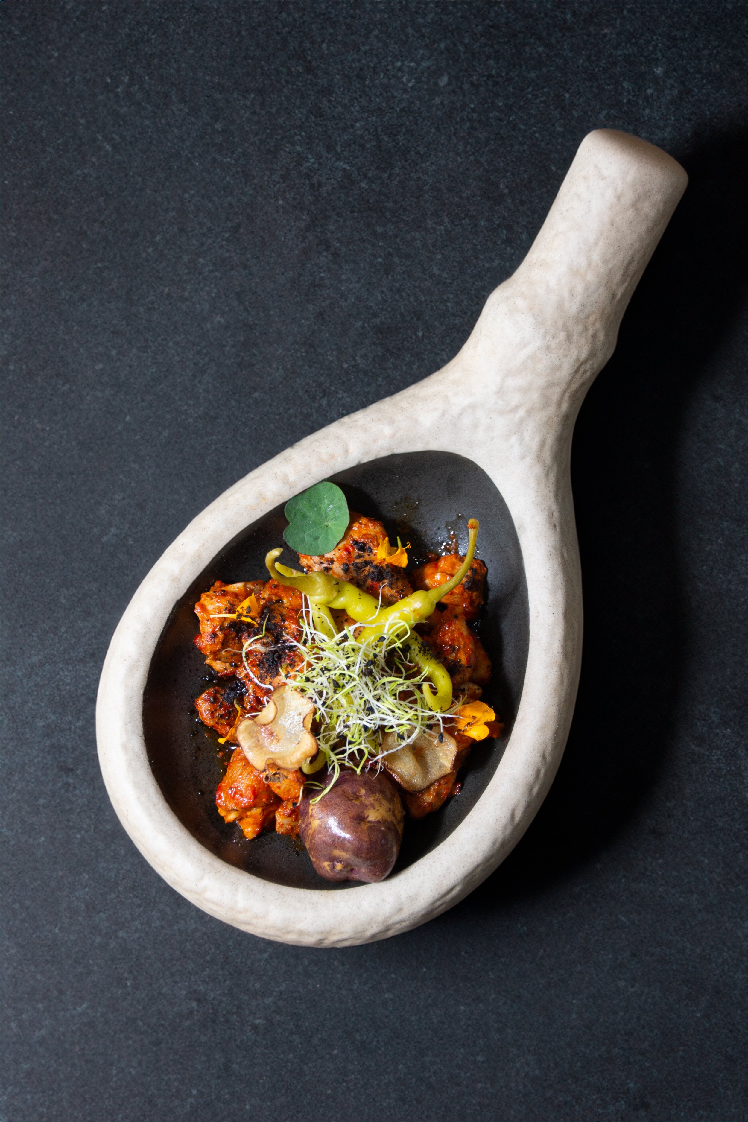 La elegancia se encuentra con lo rústico en esta toma que realza un plato de legumbres y vegetales, presentados en un bol de diseño moderno y minimalista, perfecto para destacar la vivacidad y frescura de los ingredientes.