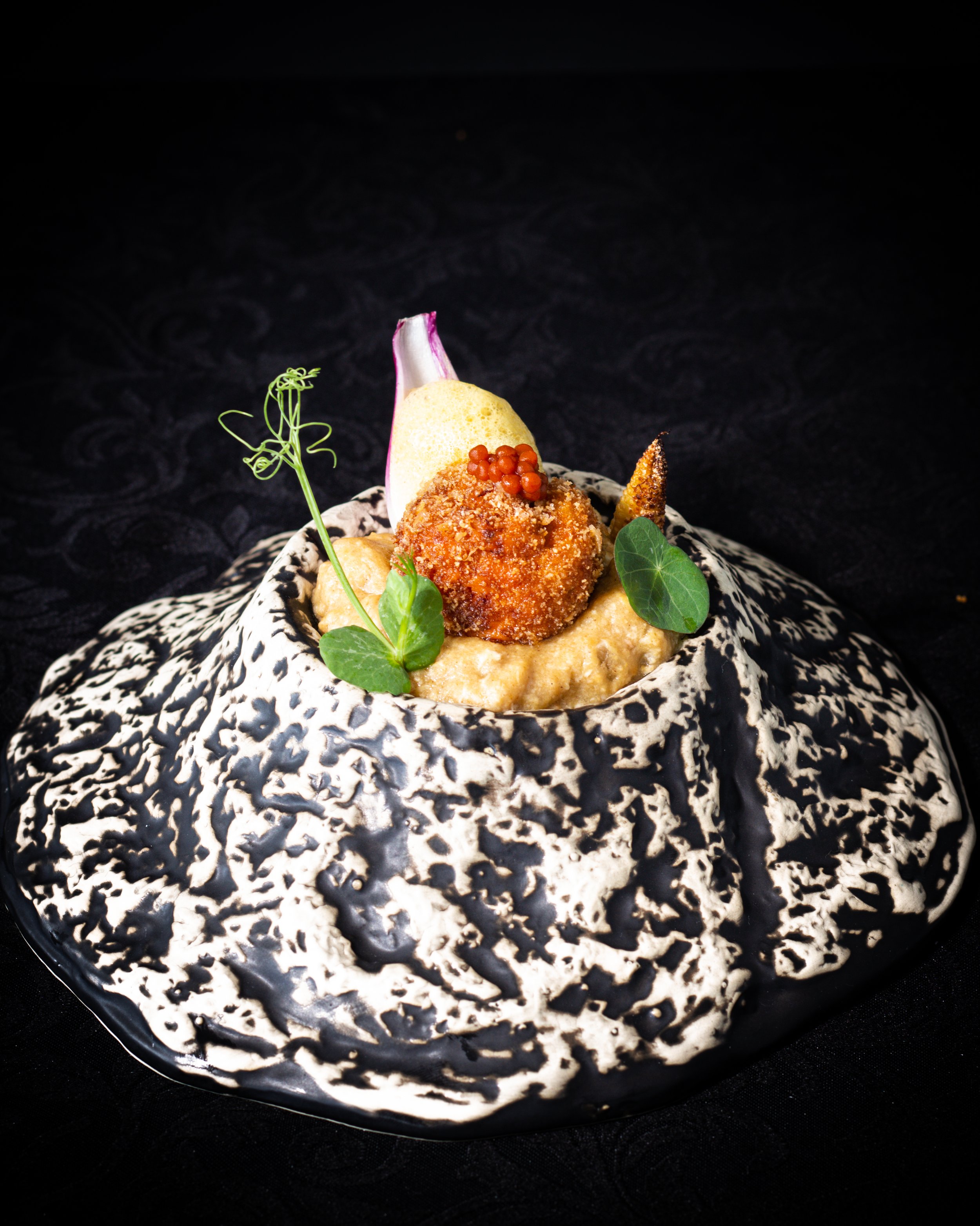 Creación culinaria de autor que destaca un plato decorativo debajo de una presentación impecable de sabores complejos y refinados, capturando la esencia de una experiencia gastronómica única y memorable.