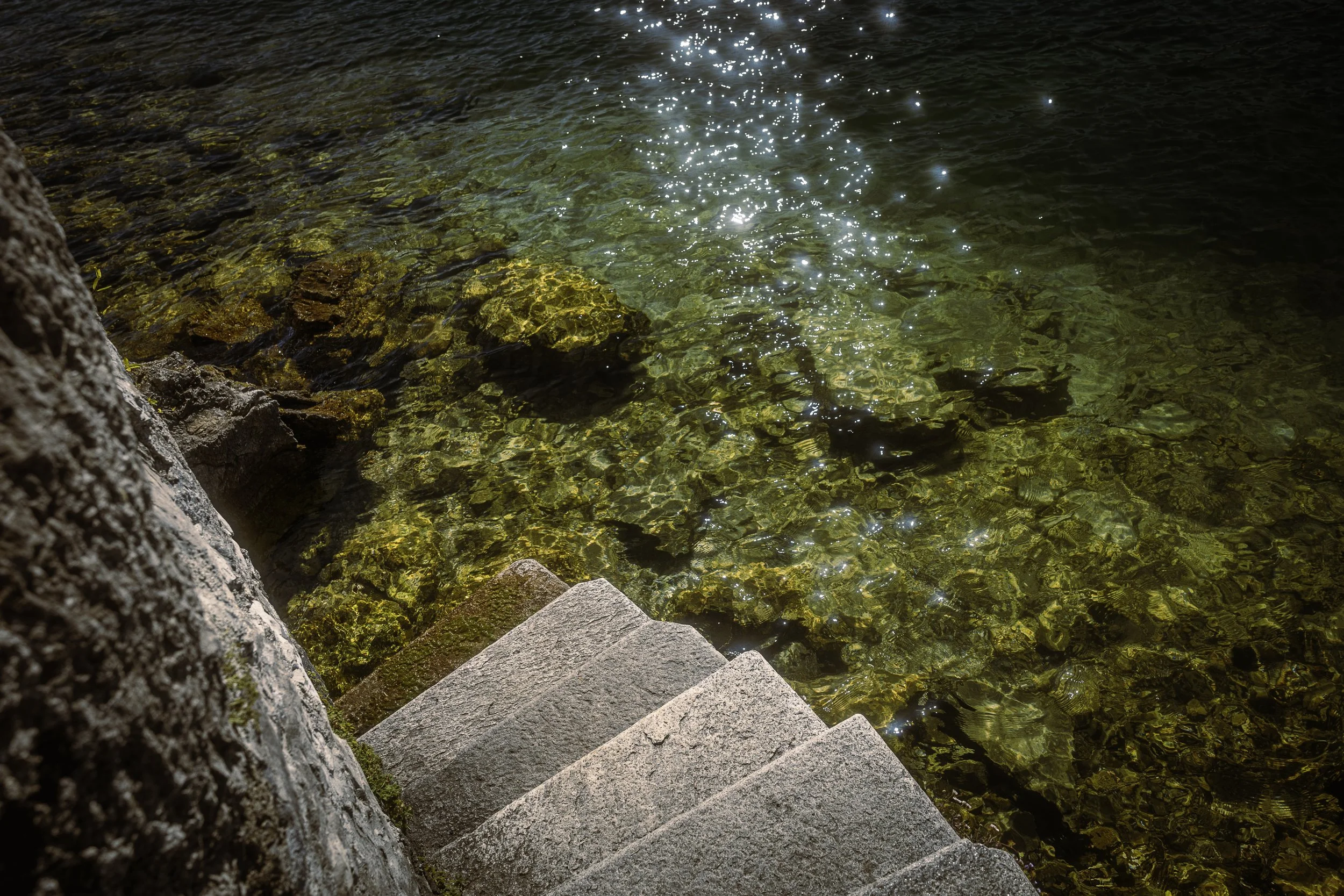 Kiviportaat johtavat vesirajaan, jossa näkyy kirkas, vihertävä vesi ja kalliopohja.