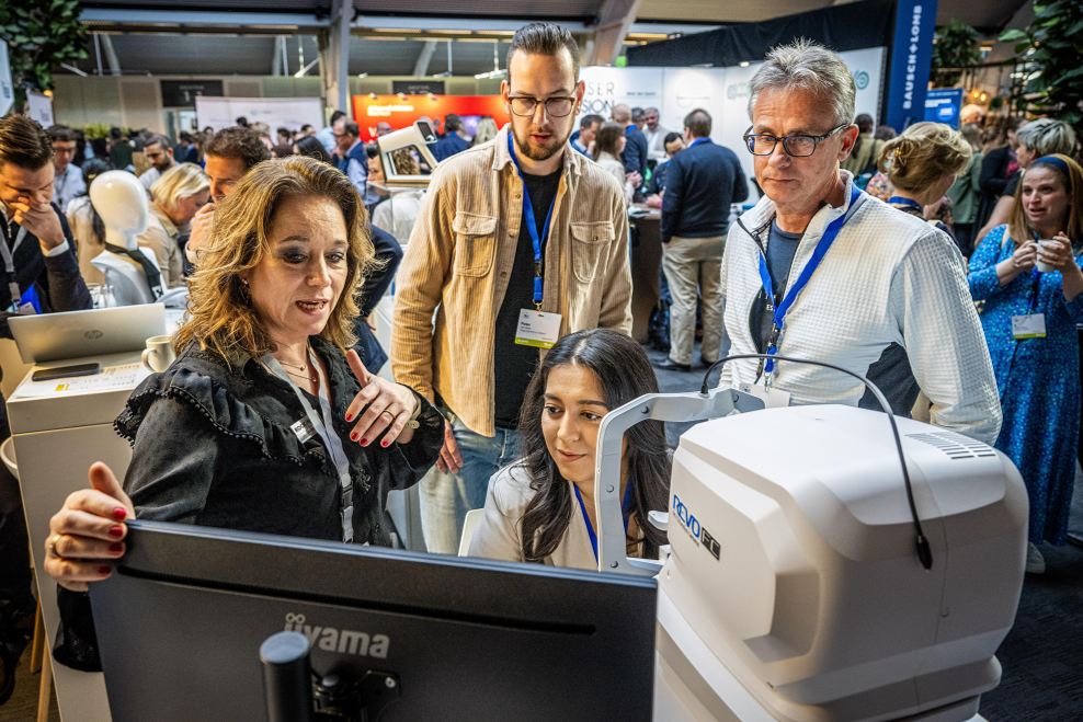 Mensen die op een technologische beurs naar een apparaat kijken.