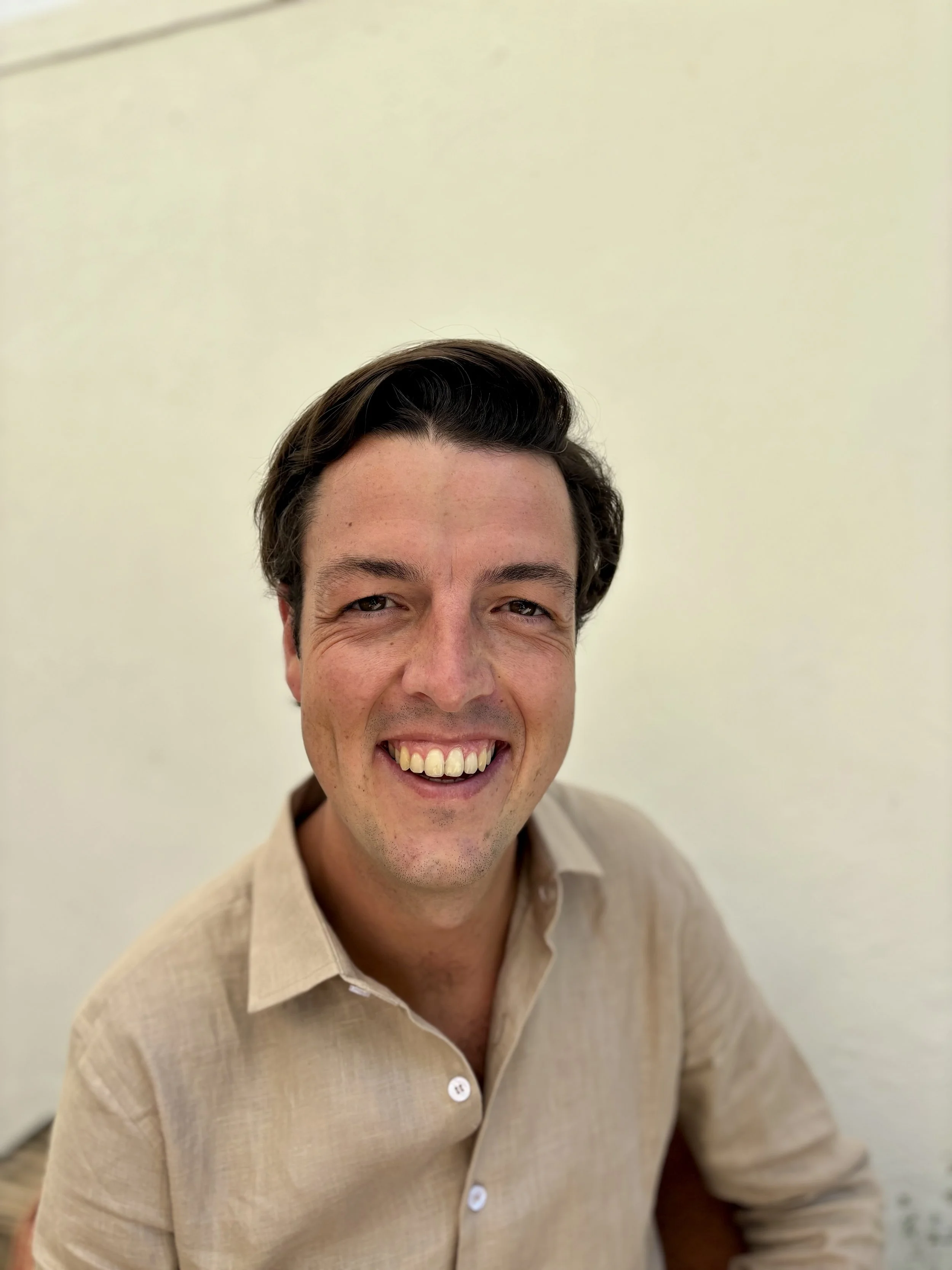 Een lachende man (Rick) met zwart haar en een beige overhemd. Eigenaar van Aristos Events.