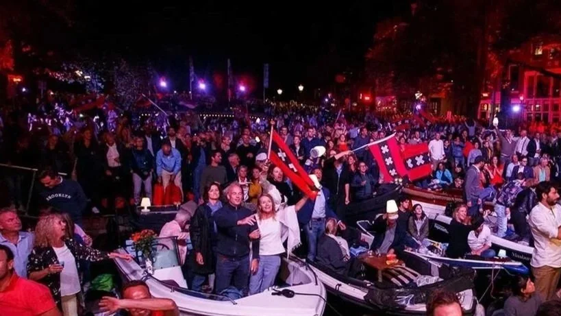 Mensen zwaaien met vlaggen tijdens het Prinsengrachtconcert in Amsterdam