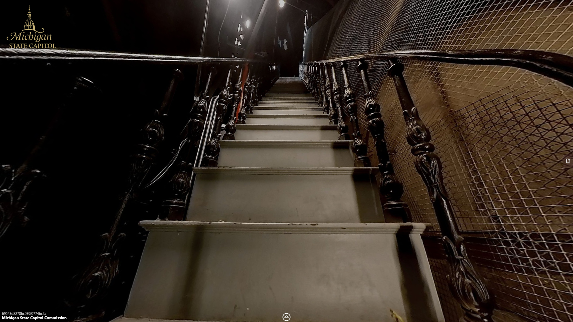 image of a narrow stairway and railing leading upward between metal walls.