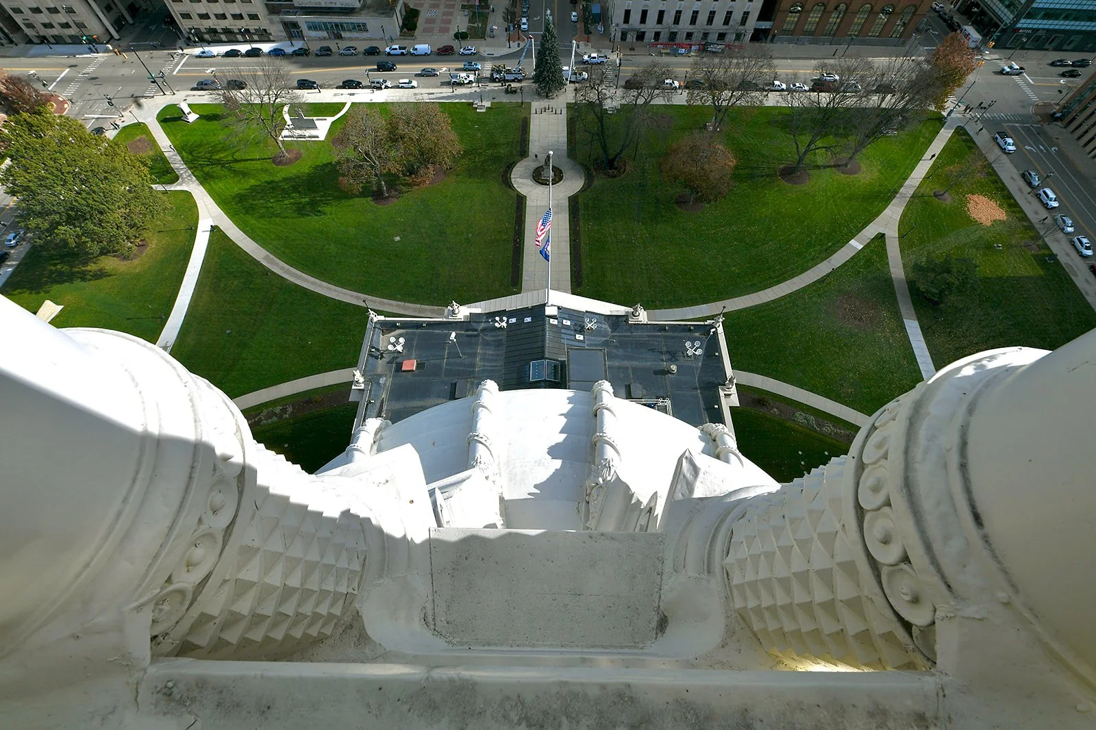 image looking downward at the outside of the capitol dome from the top, showing the curvature of the dome, the capitol rooftop, and the lawn below.