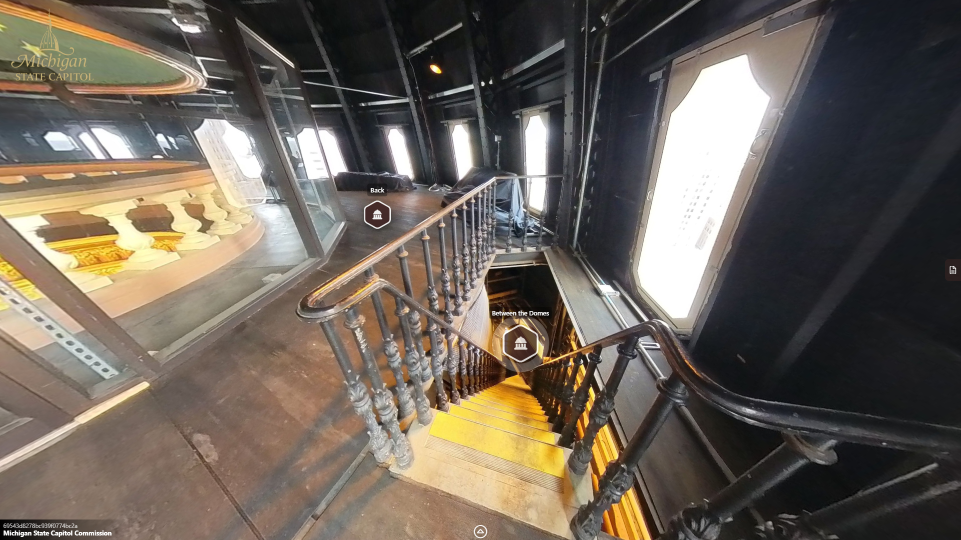image of a narrow stairway and railign leading downward into the level below, surrounded by octagonal windows.