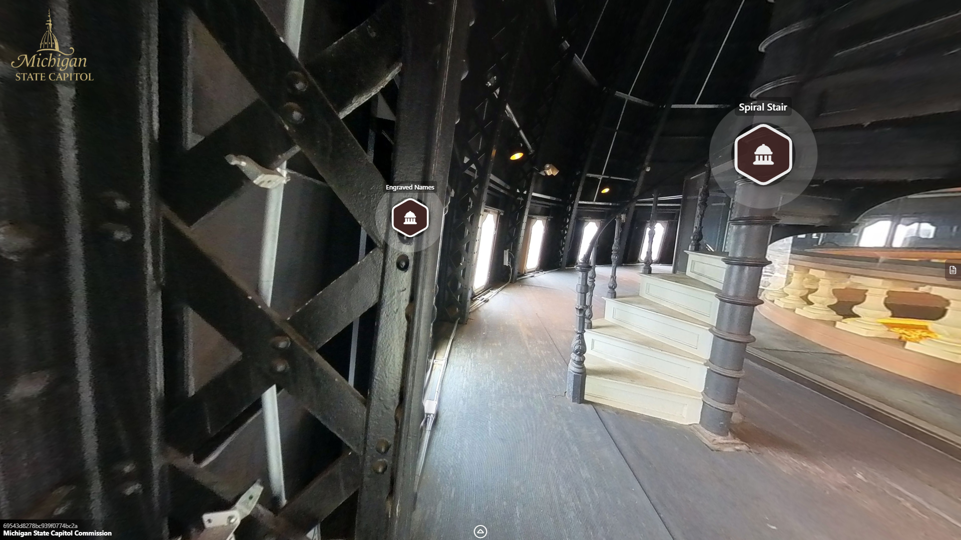 closeup image of a metal truss or beam, with a spiral staircase in the background.