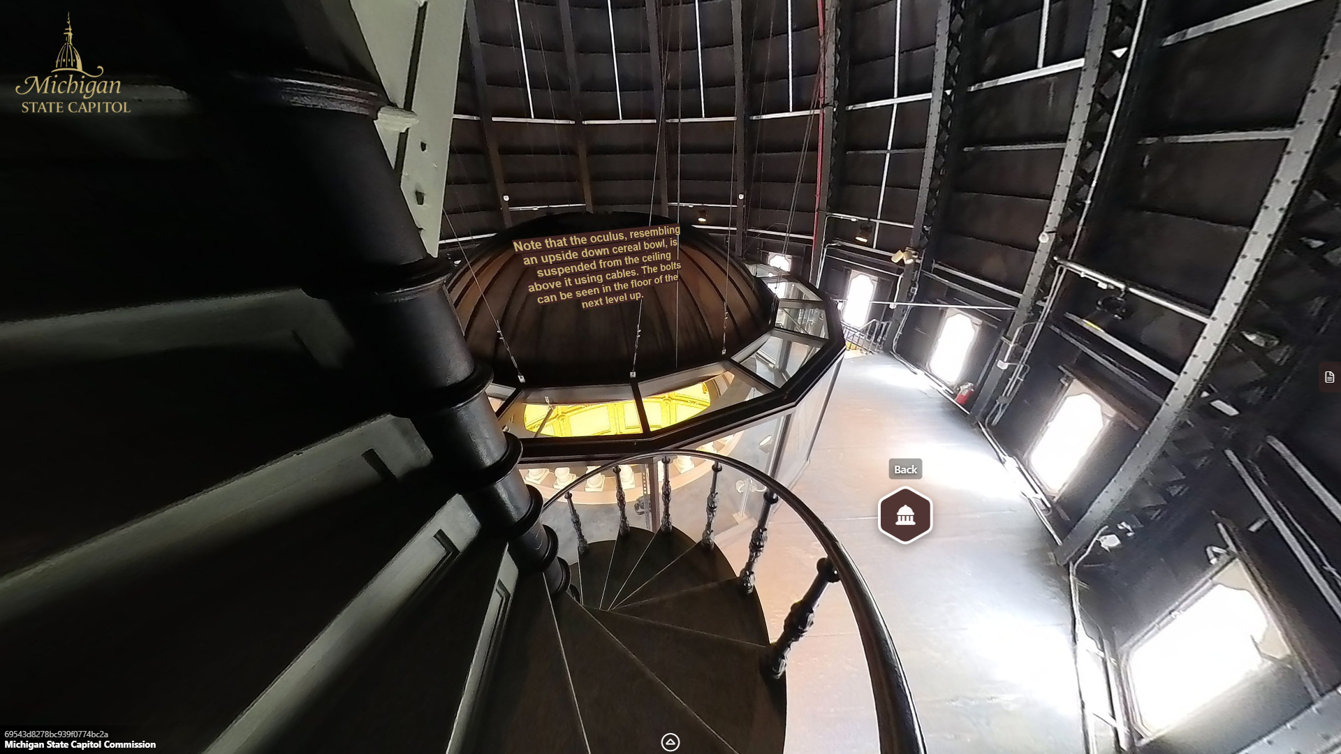 image of a large open space with windows and metal walls and trusses. A metal staircase leads upward on the left side above a circular glass and metal enclosure below.