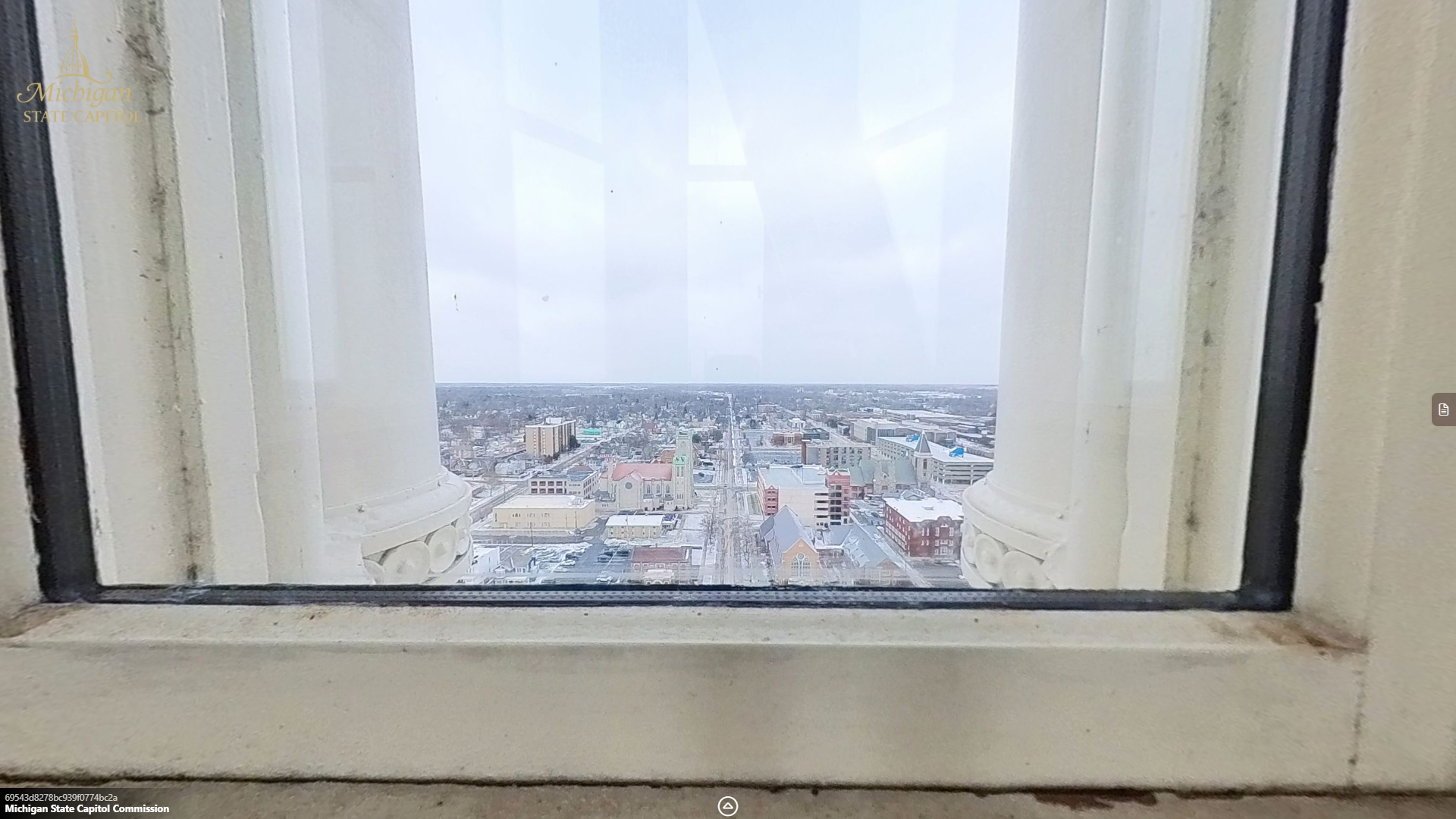 view through a window of building and church rooftops along a street.