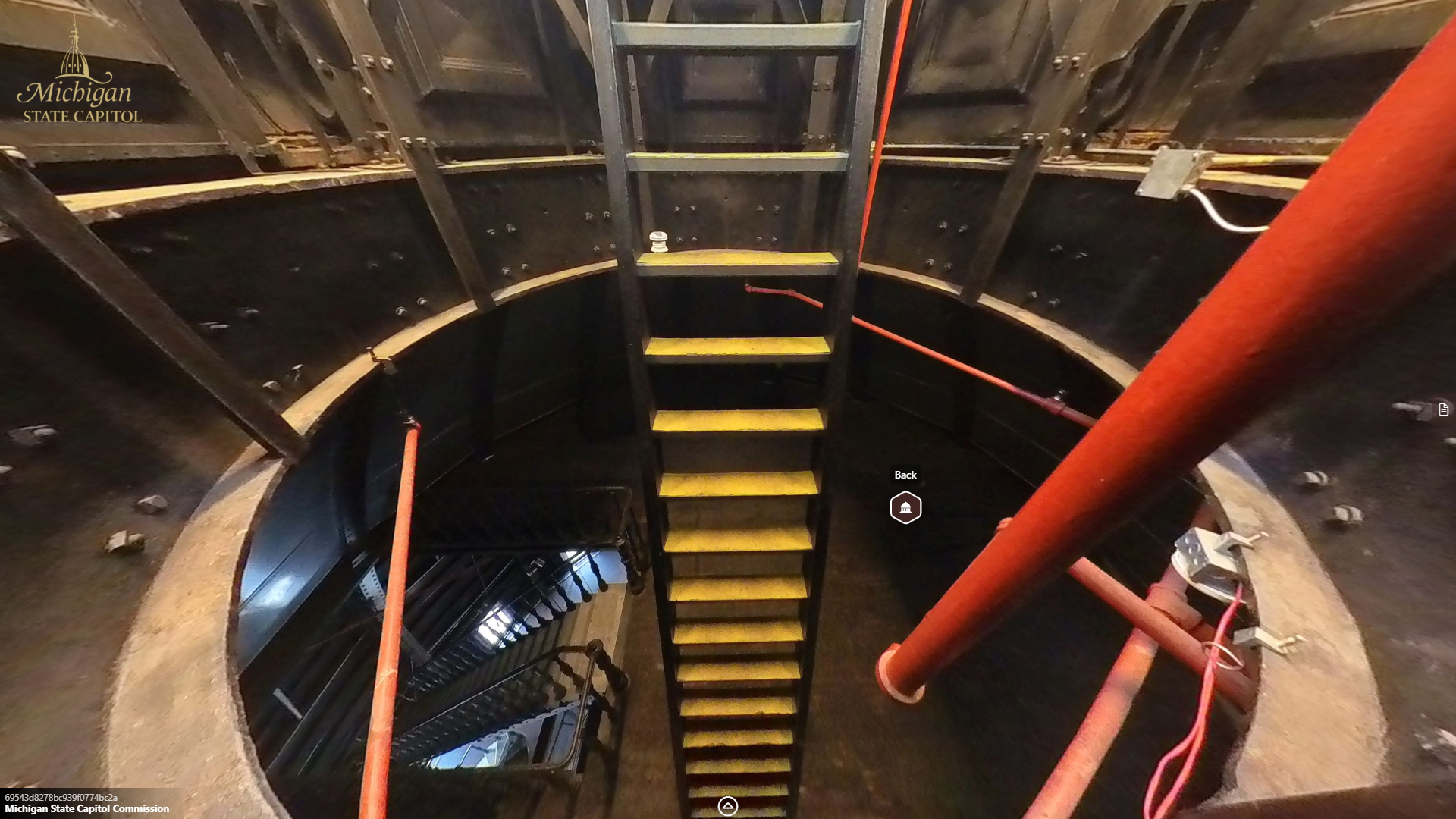 image from inside a narrow metal circular opening, with a metal ladder or stair leading downward, with a seperate metal stair and railing below leading further downward.