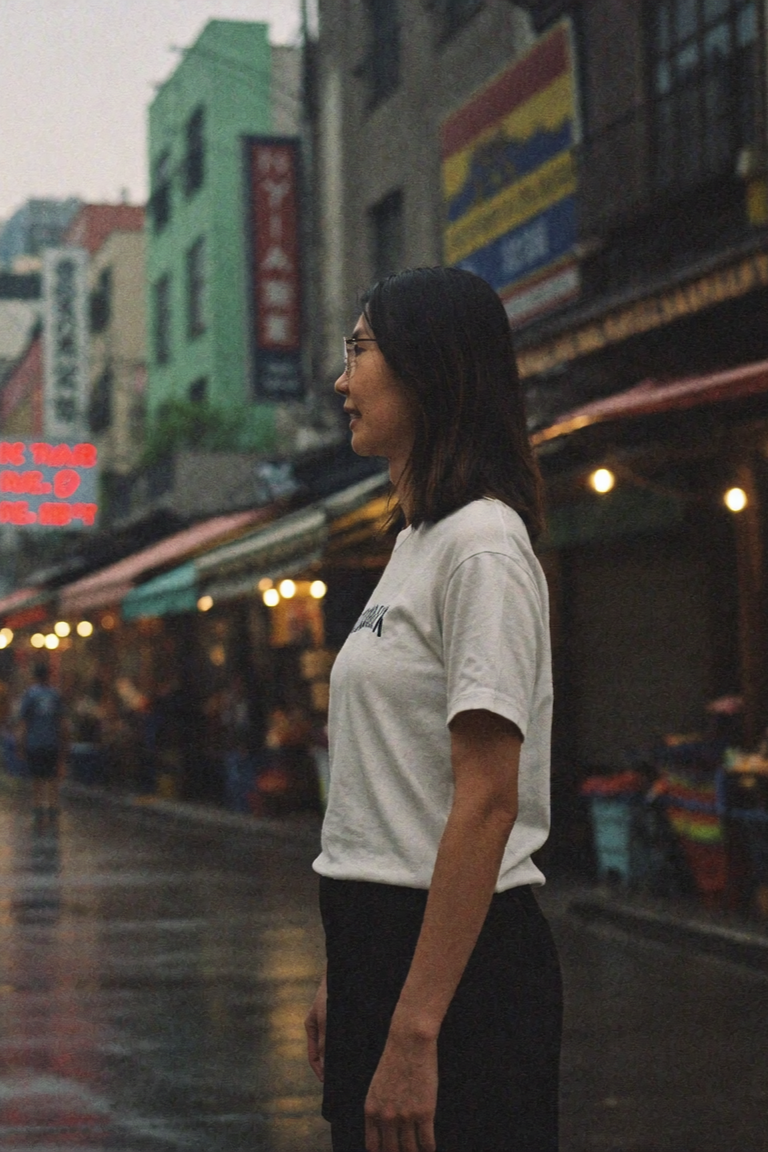 Smiling person with glasses wearing a light green cardigan and peach top against a white background.