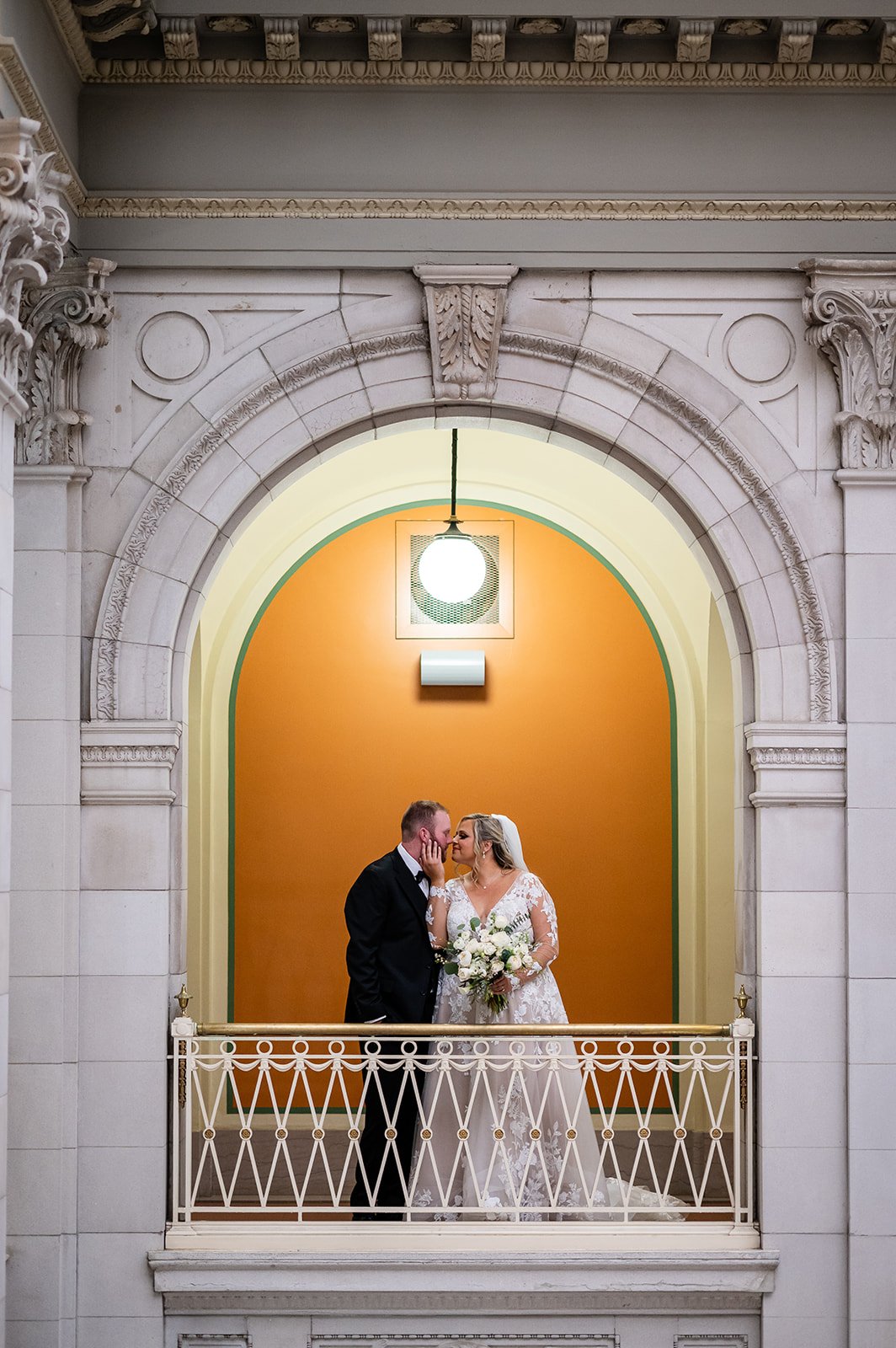 Woman and Man Posed in front of orange wall with marble columns around them