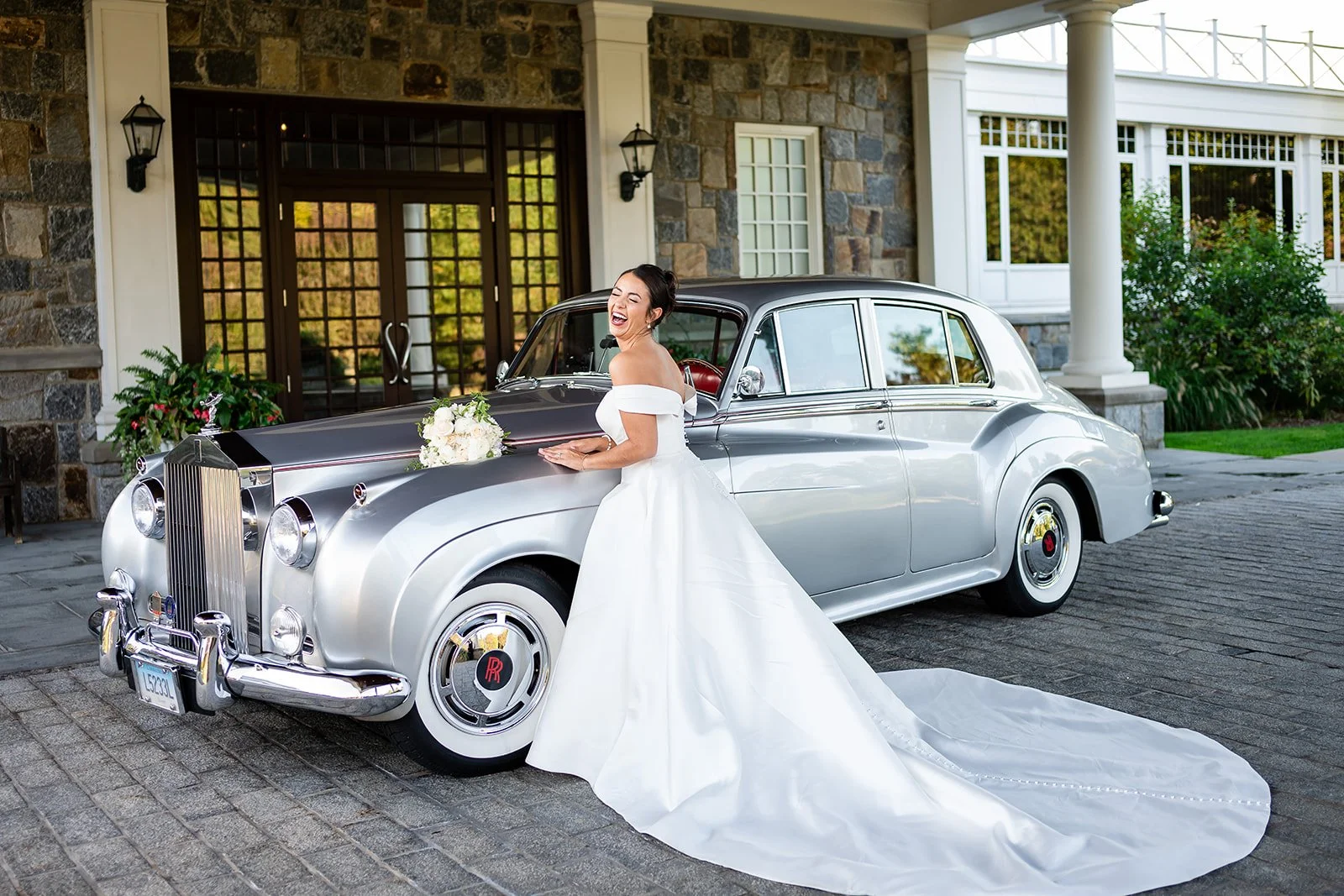 woman in white dress standing in front of silver Rolls Royce