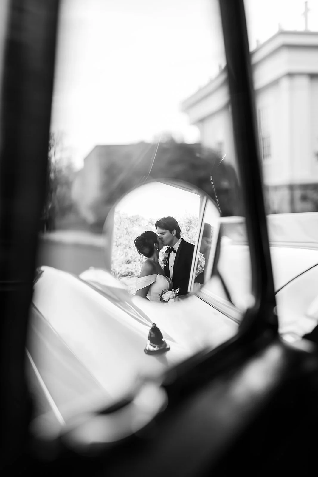 woman and man kissing image taken through a Rolls Royce mirror