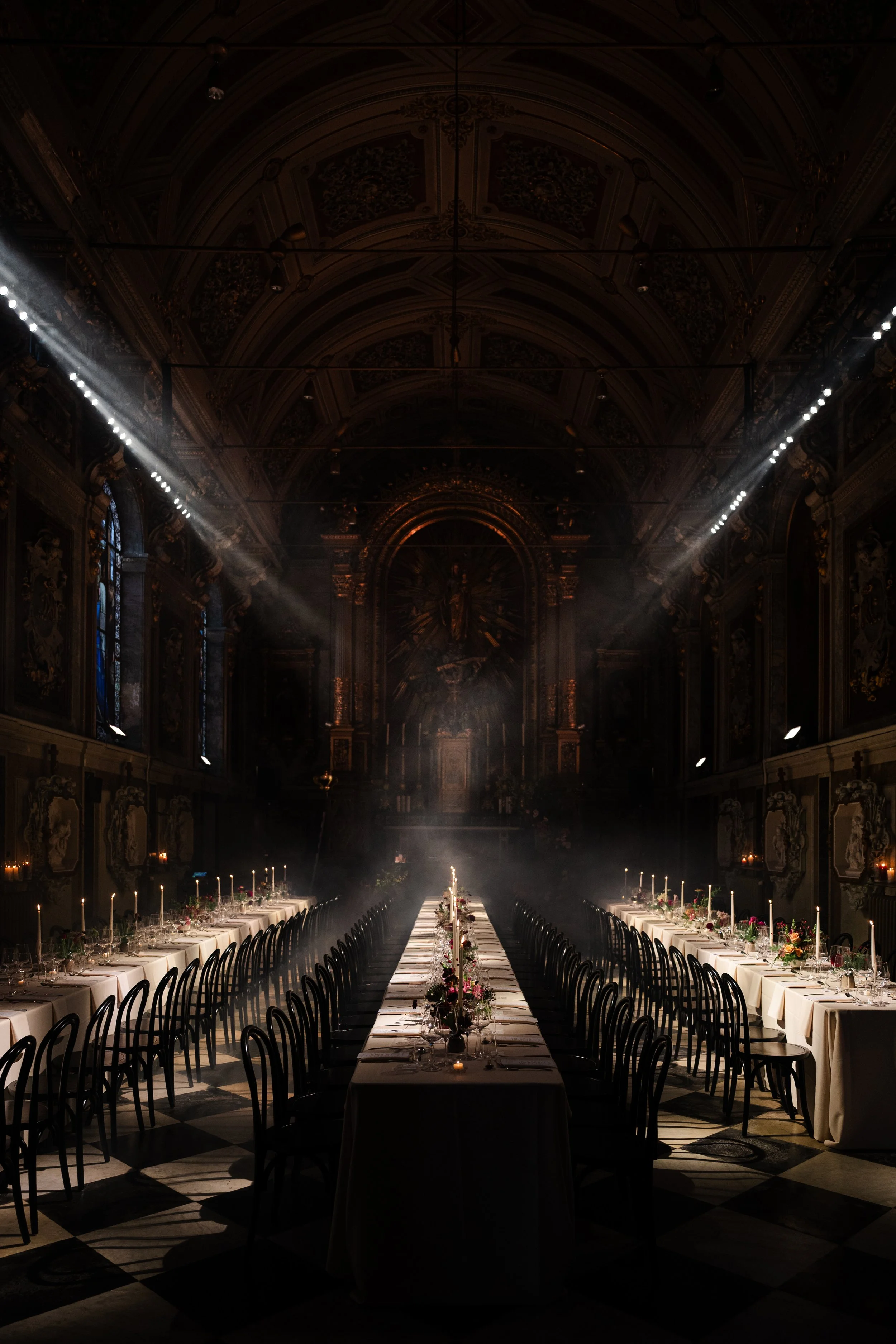 Witte schoenen, een bloemenboeket met witte rozen en groene bladeren, en twee gouden trouwringen liggen op een zwarte stenen tafel.