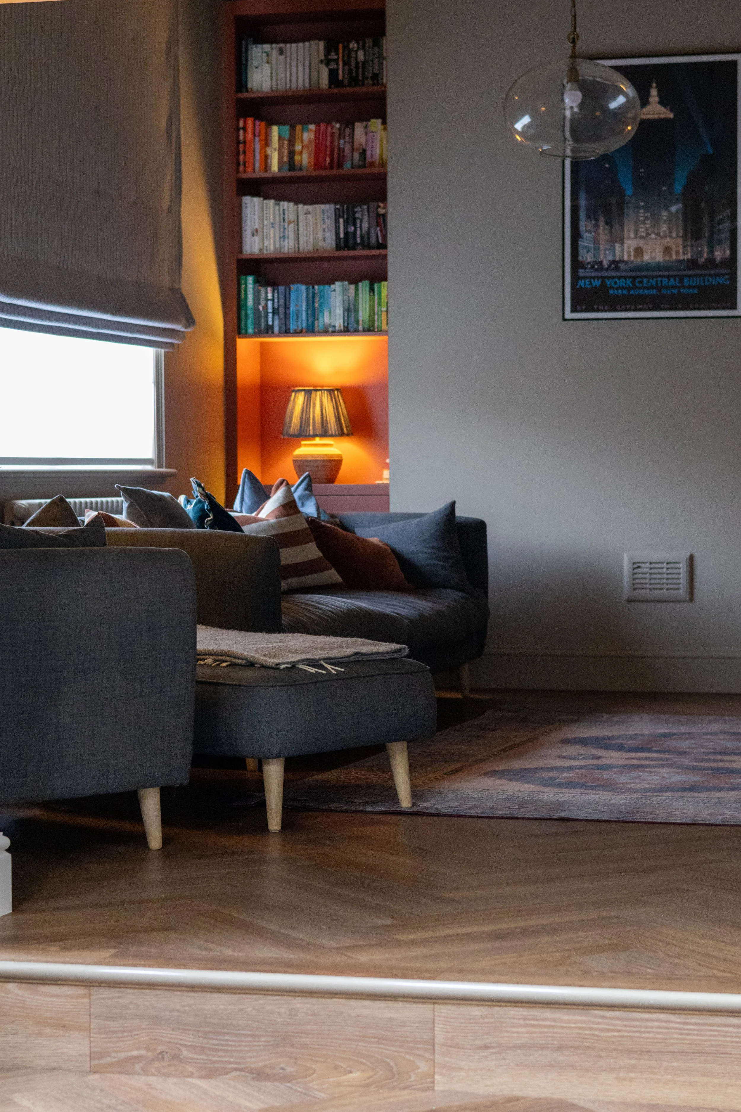Twin terracotta bookshelves either side of a framed New York print, each lit with a ceramic lamp