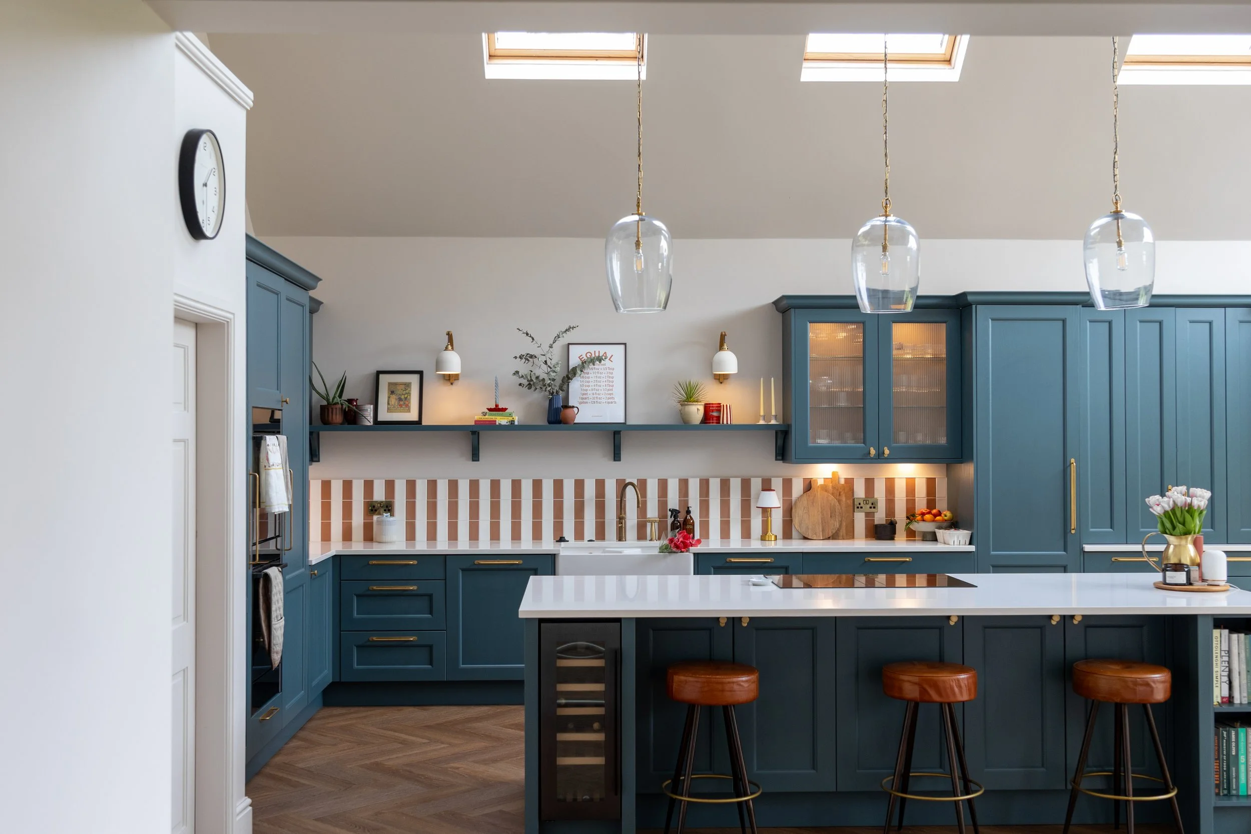 Teal kitchen with pendant lighting, roof skylights and dining table with tulips in the foreground