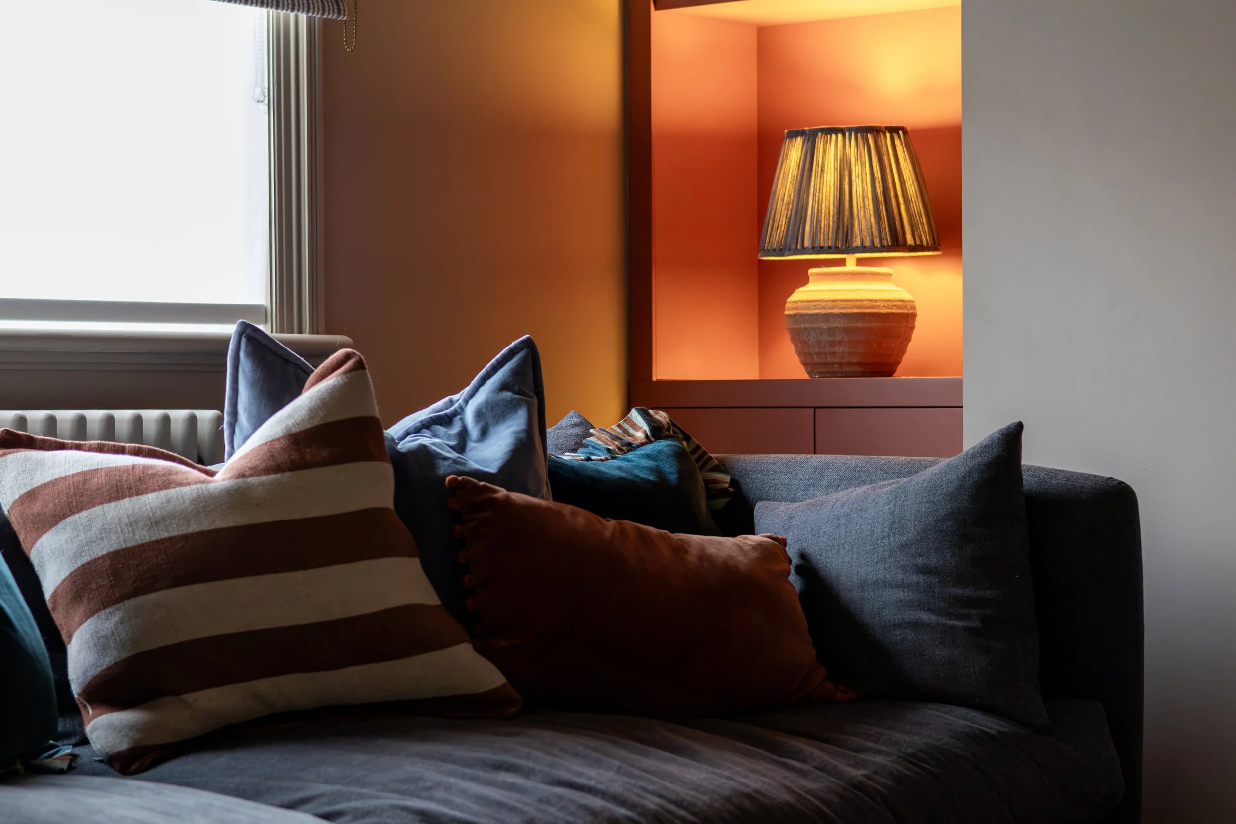 Close-up of terracotta, blue and striped scatter cushions on a grey sofa