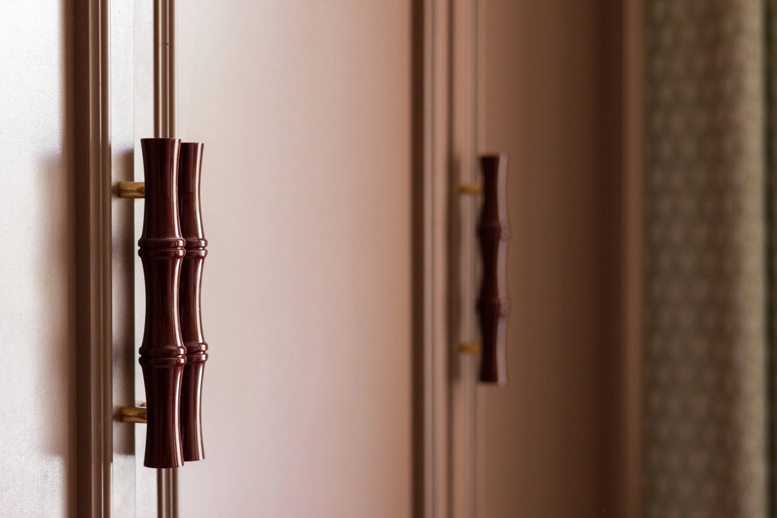 Burgundy bamboo-style door pulls with brass fittings on fitted wardrobe doors