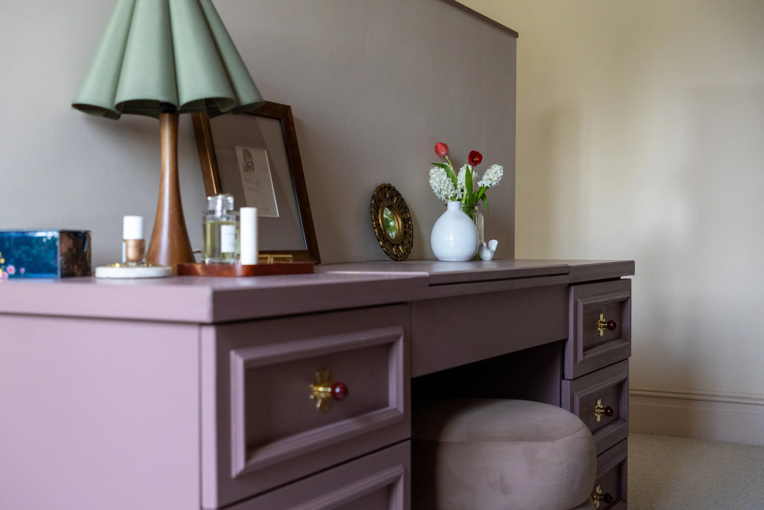 Dressing table with green pleated lamp, perfume tray and trailing eucalyptus