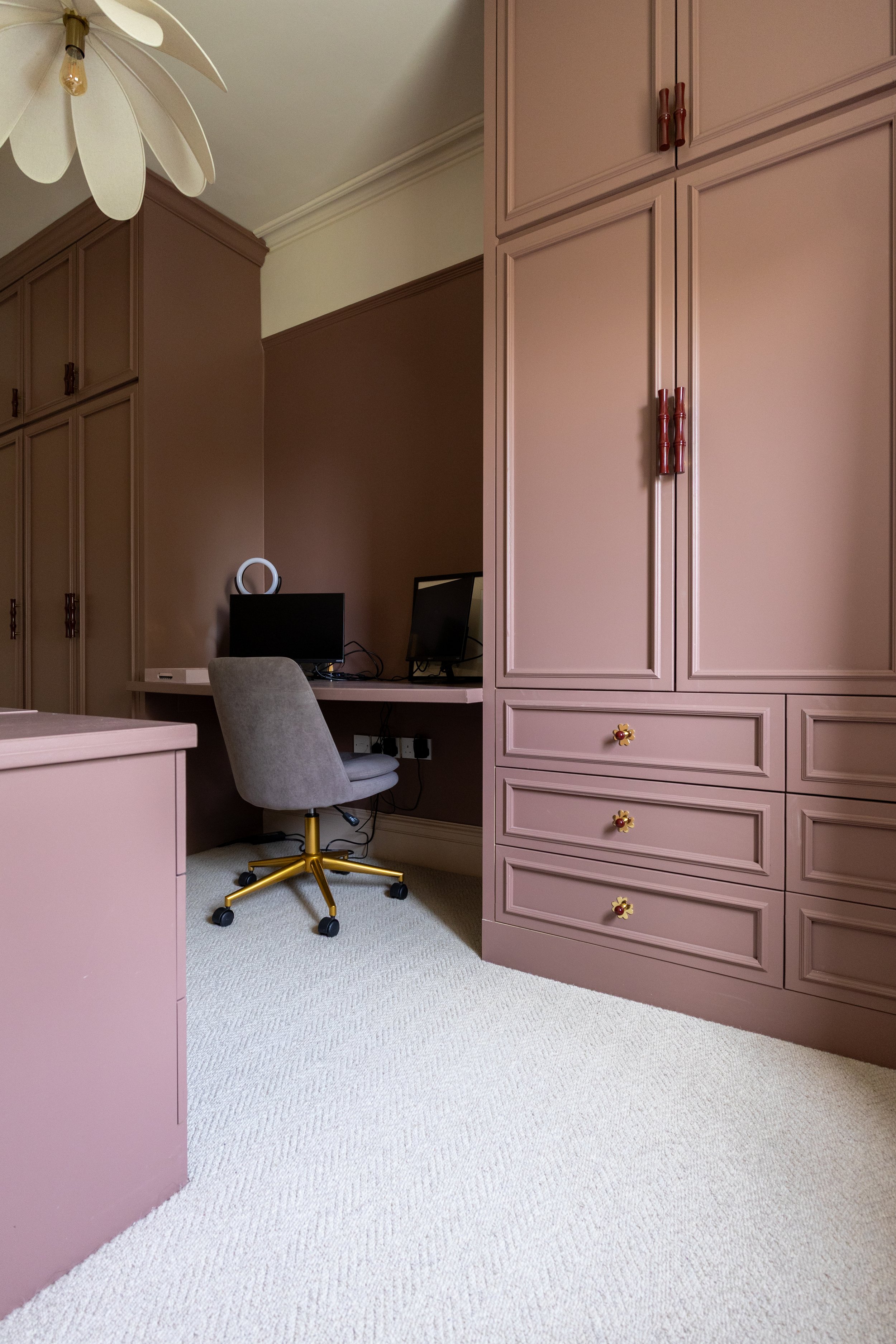 Fitted wardrobes opening onto a built-in desk nook with dual monitors and velvet office chair