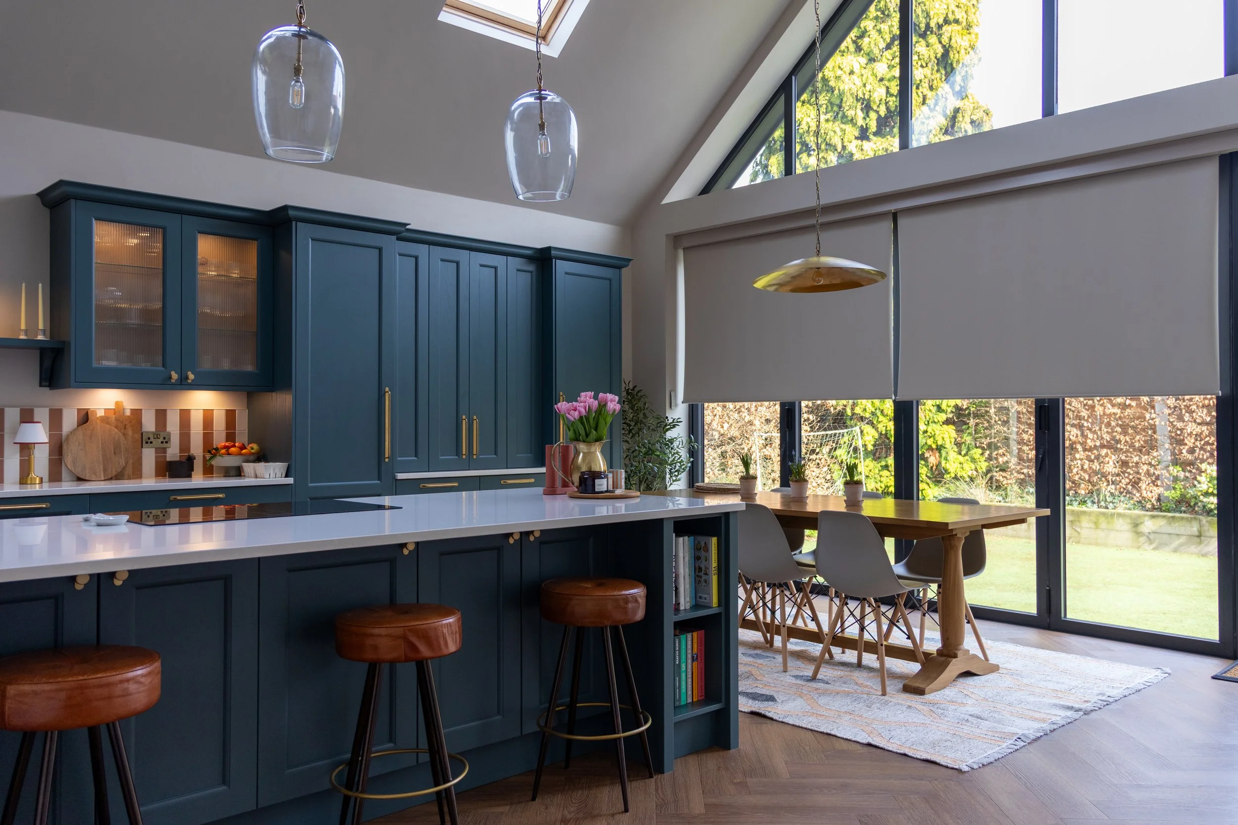 Teal shaker kitchen with open shelving, glass pendant lights and dining area beyond