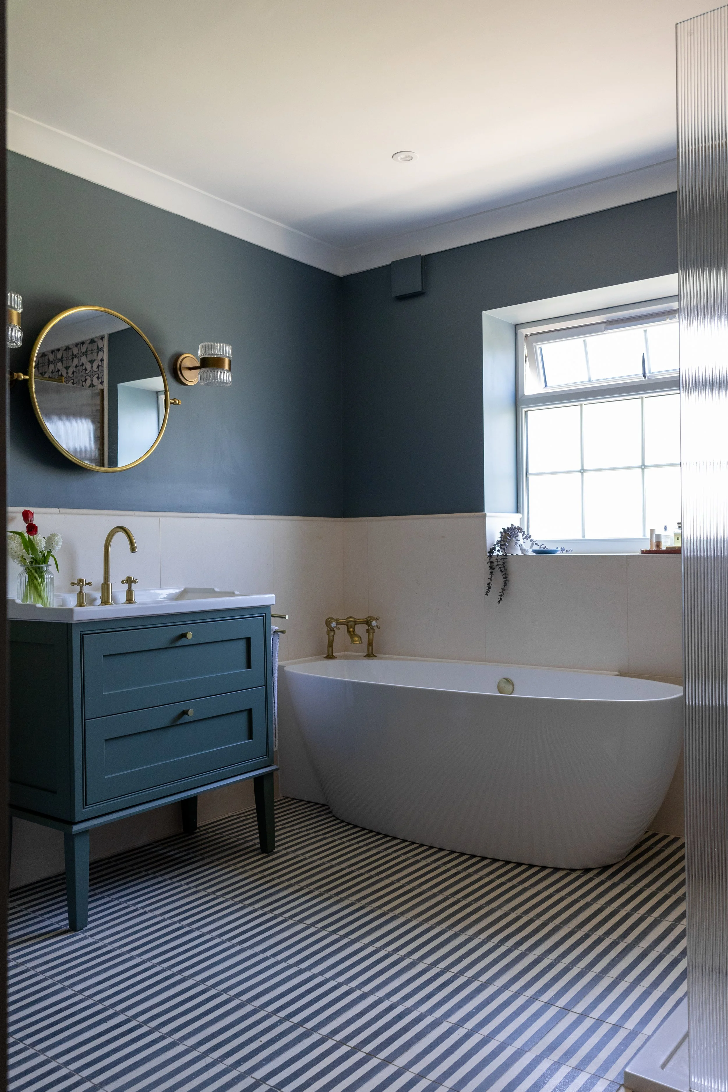 Bathroom view showing teal vanity, freestanding tub and reeded glass shower screen